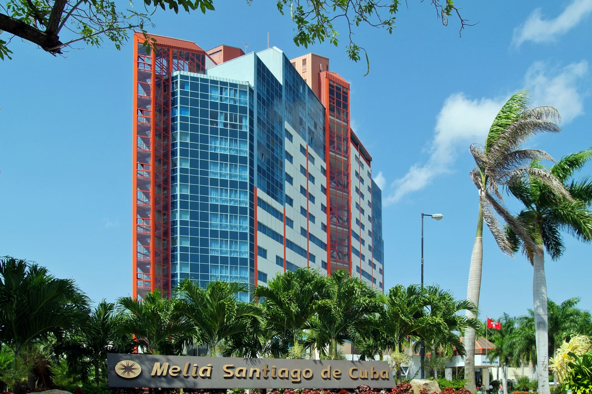 a tall building with palm trees and a sign