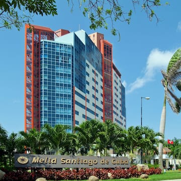 a tall building with palm trees and a sign