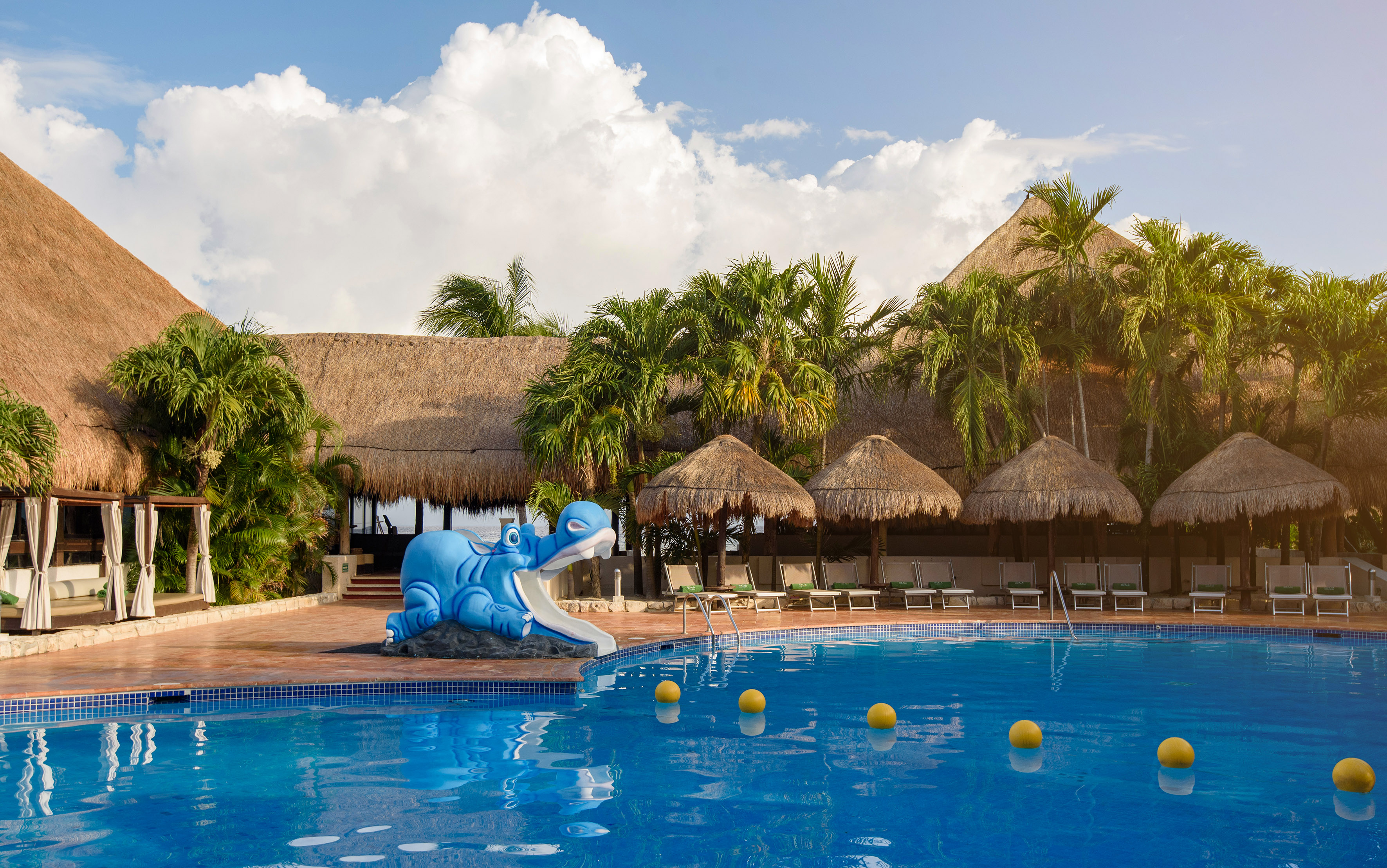 a pool with a blue dinosaur statue and palm trees