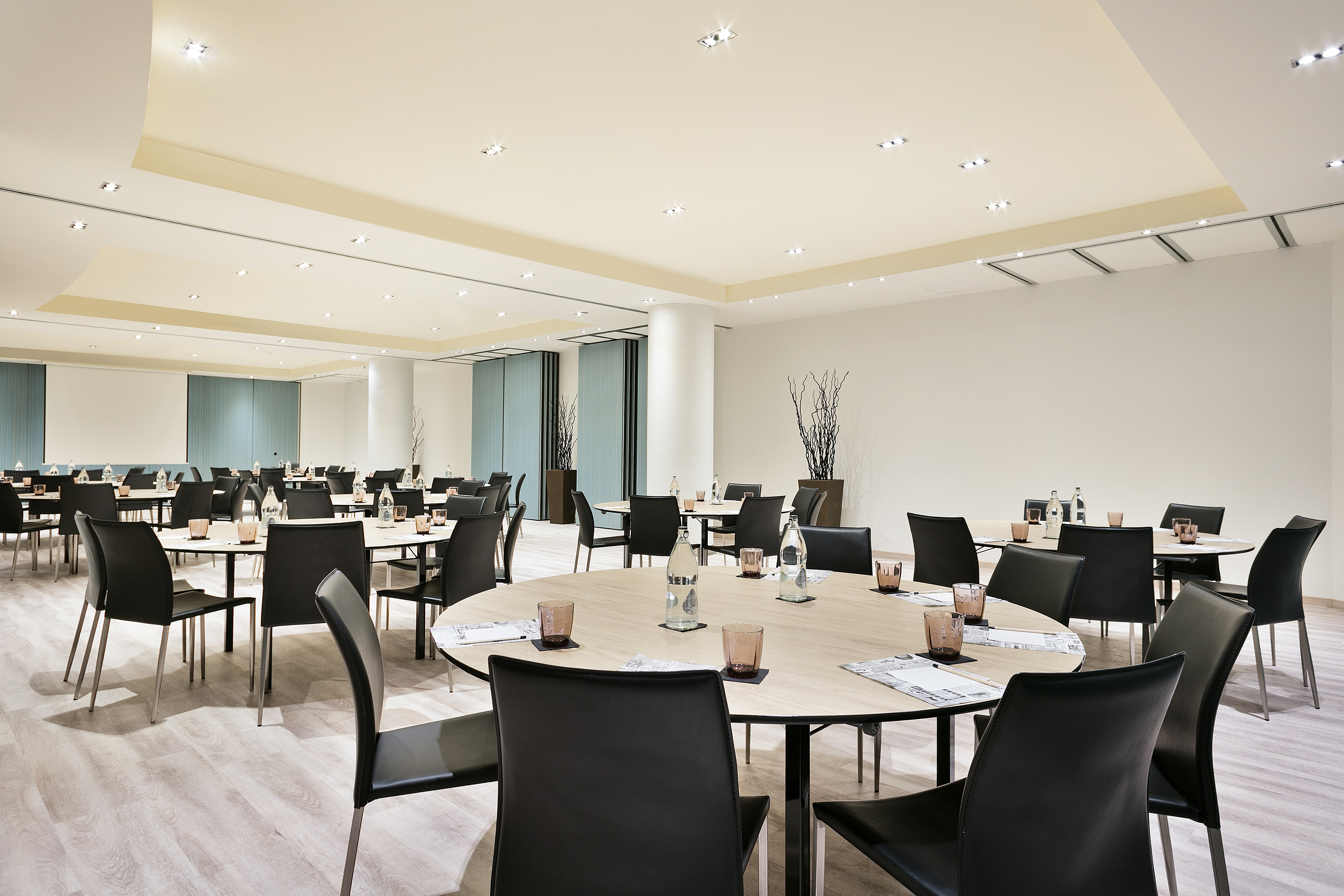 Spacious conference room with round tables, black chairs, and projector screen. - GRACIA - فندق برشلونة كوندال مار(Condal Mar) المنتسب لـ Melia, برشلونة