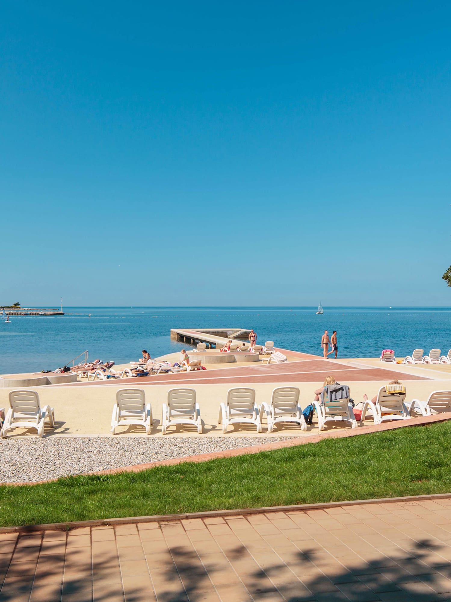 a beach with chairs and people on the water
