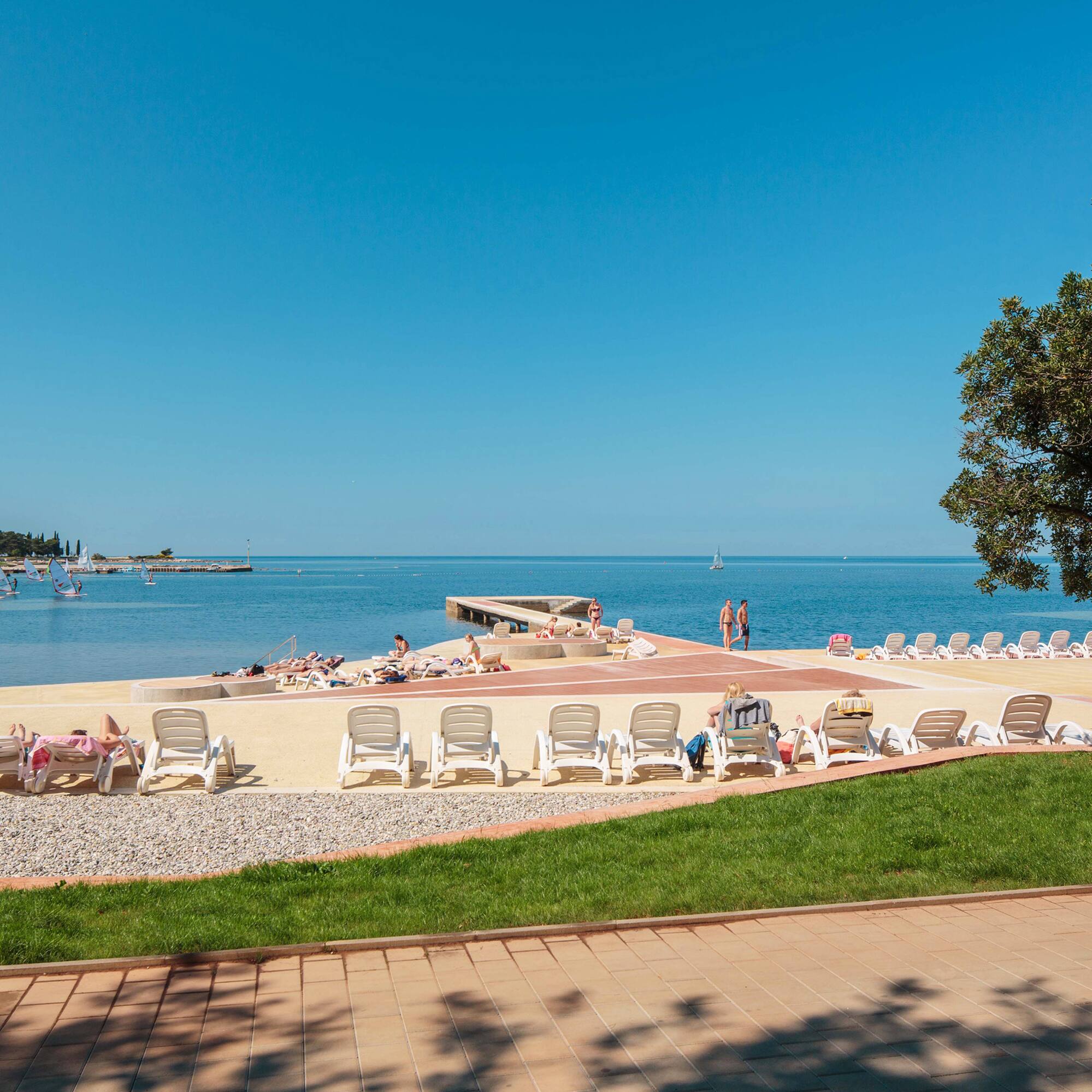 a beach with chairs and people on the water