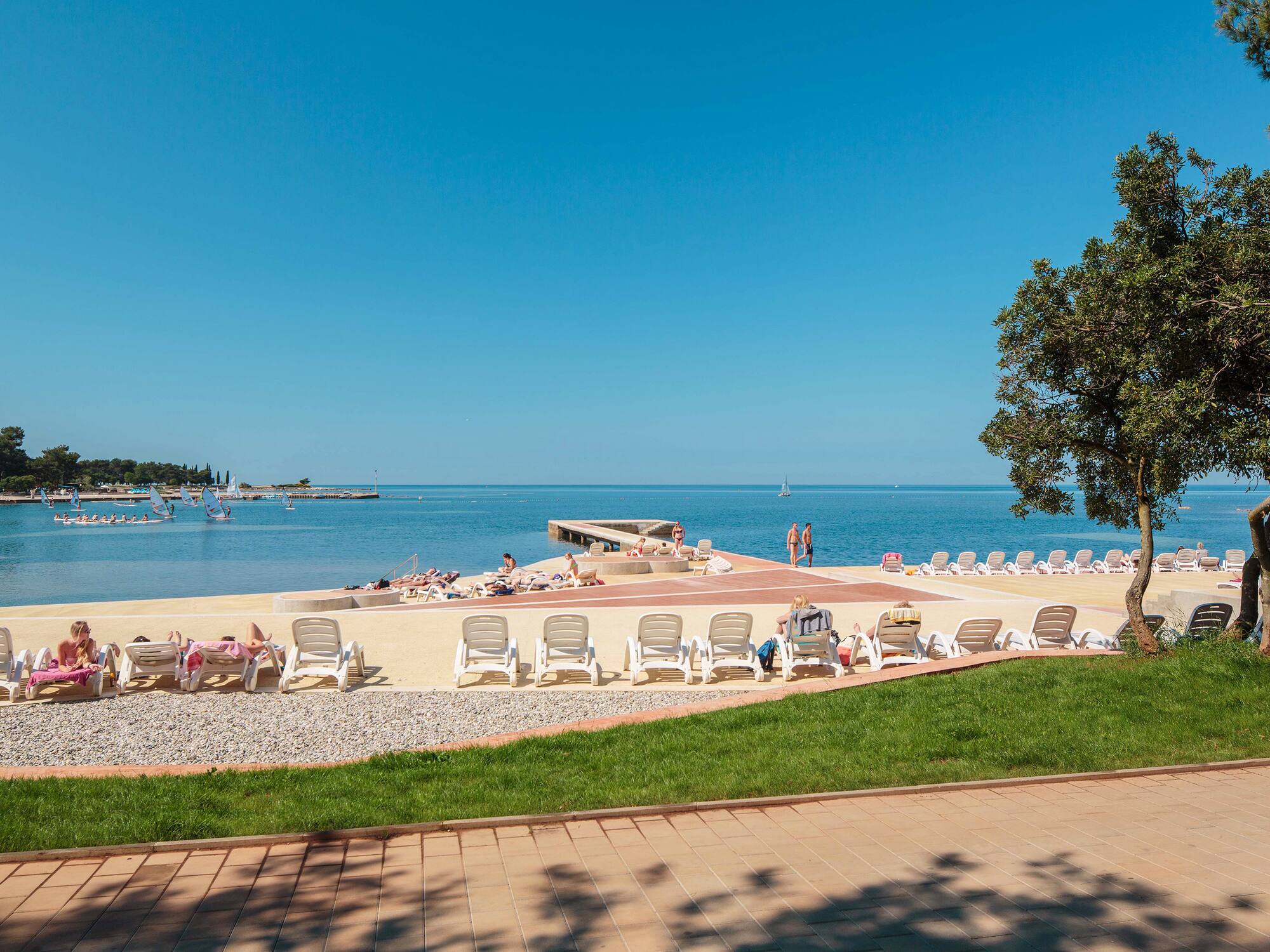 a beach with chairs and people on the water