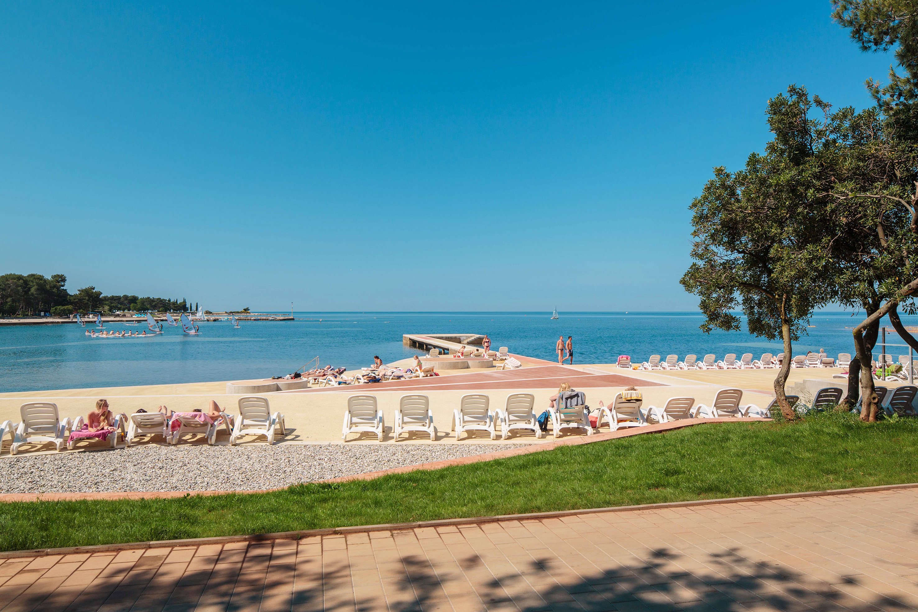 a beach with chairs and people on the water