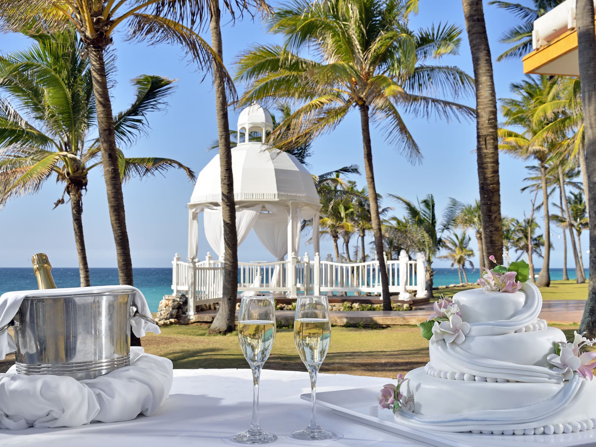 a white table with two tiered cakes and champagne glasses on it