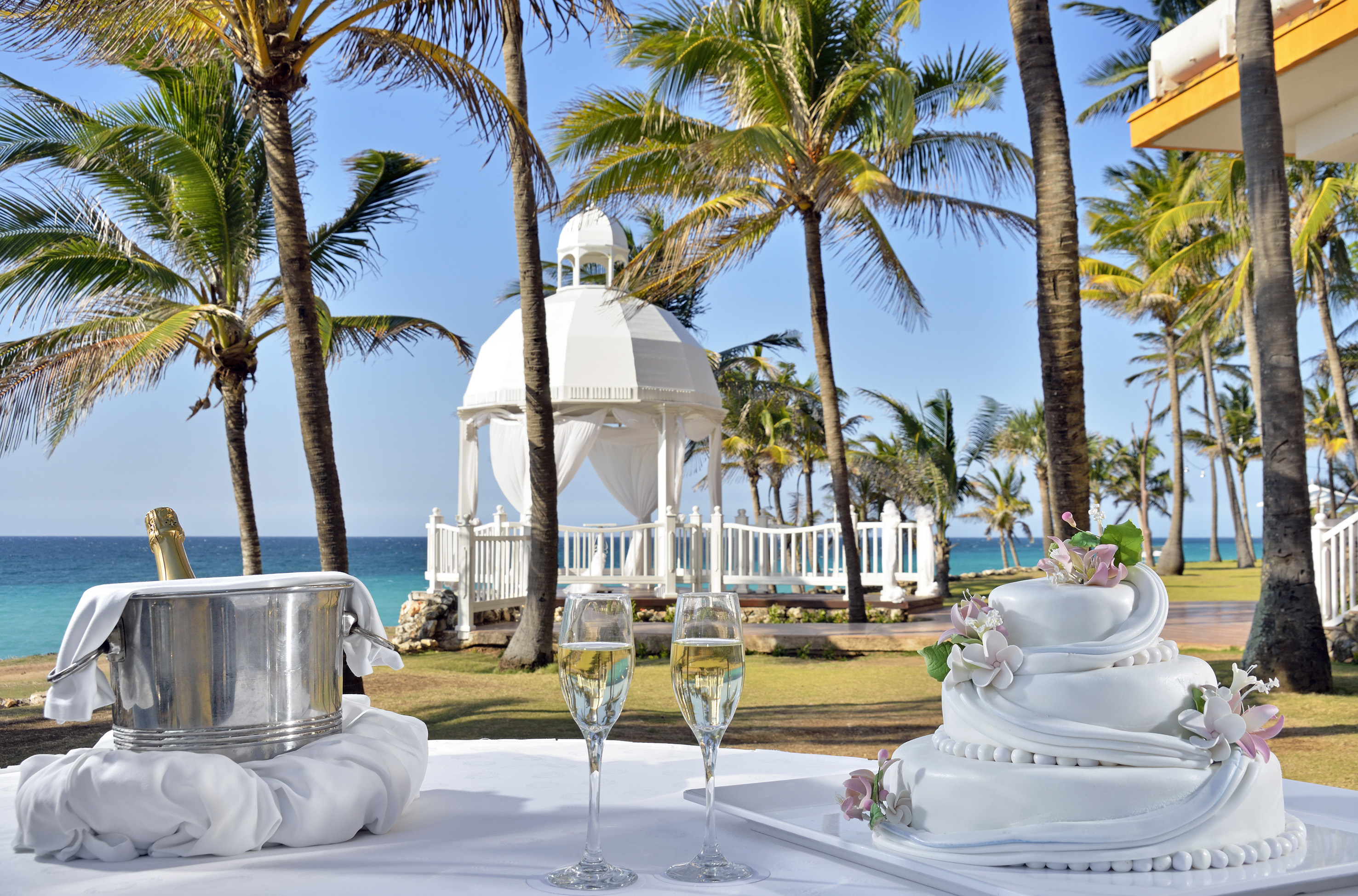 a white table with two tiered cakes and champagne glasses on it