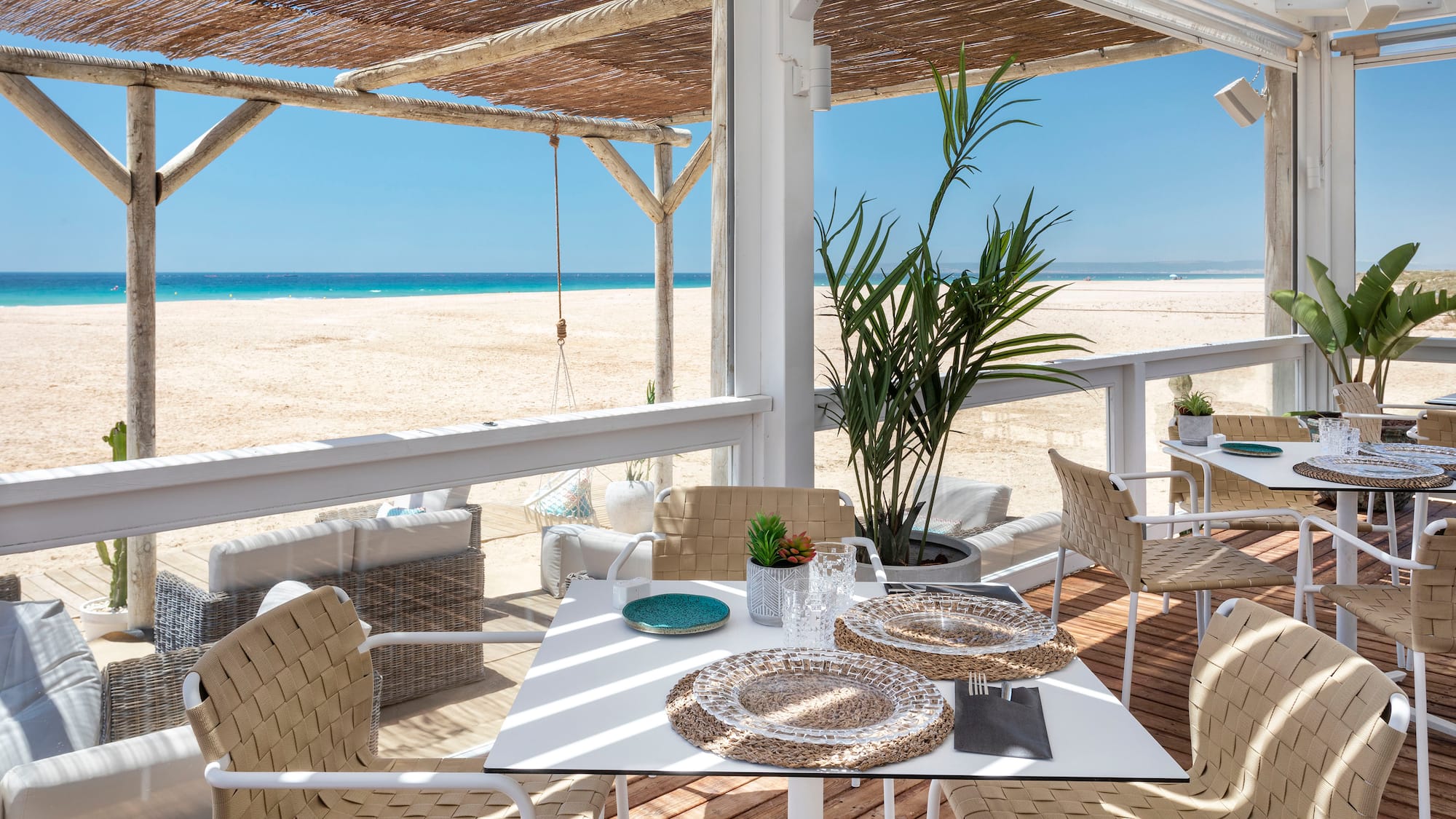 a table and chairs on a deck with a beach view