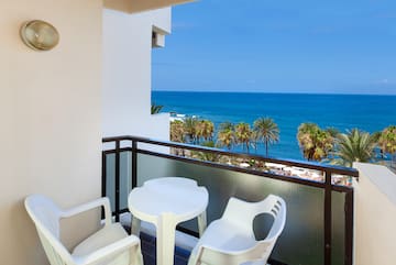 a balcony with chairs and a table overlooking the ocean