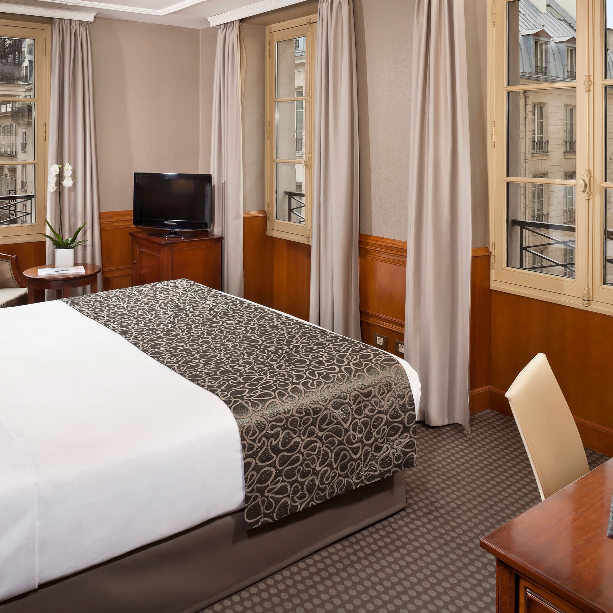 a room with a bed and a desk and a television