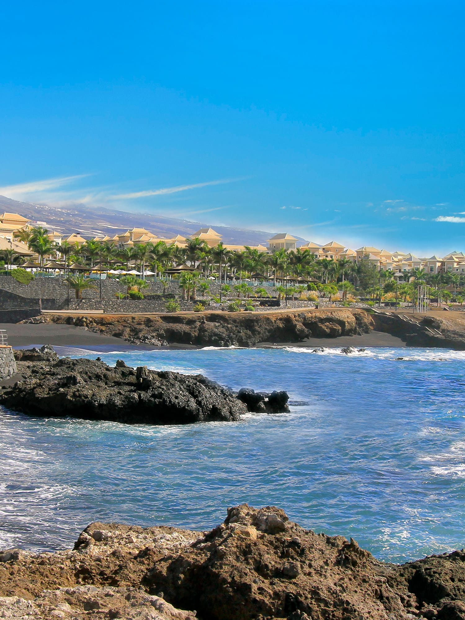 a rocky beach with buildings in the background