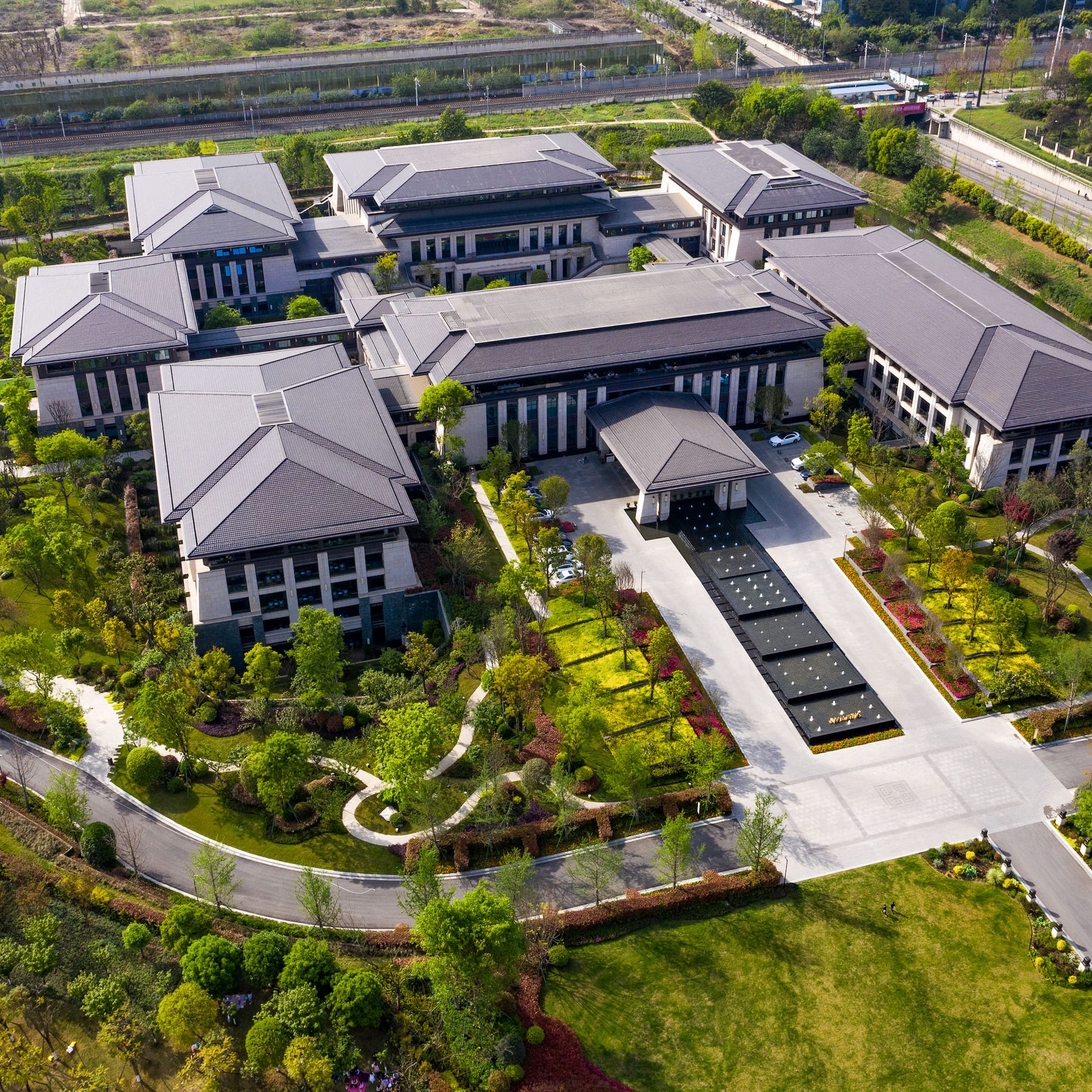a large building with a driveway and trees