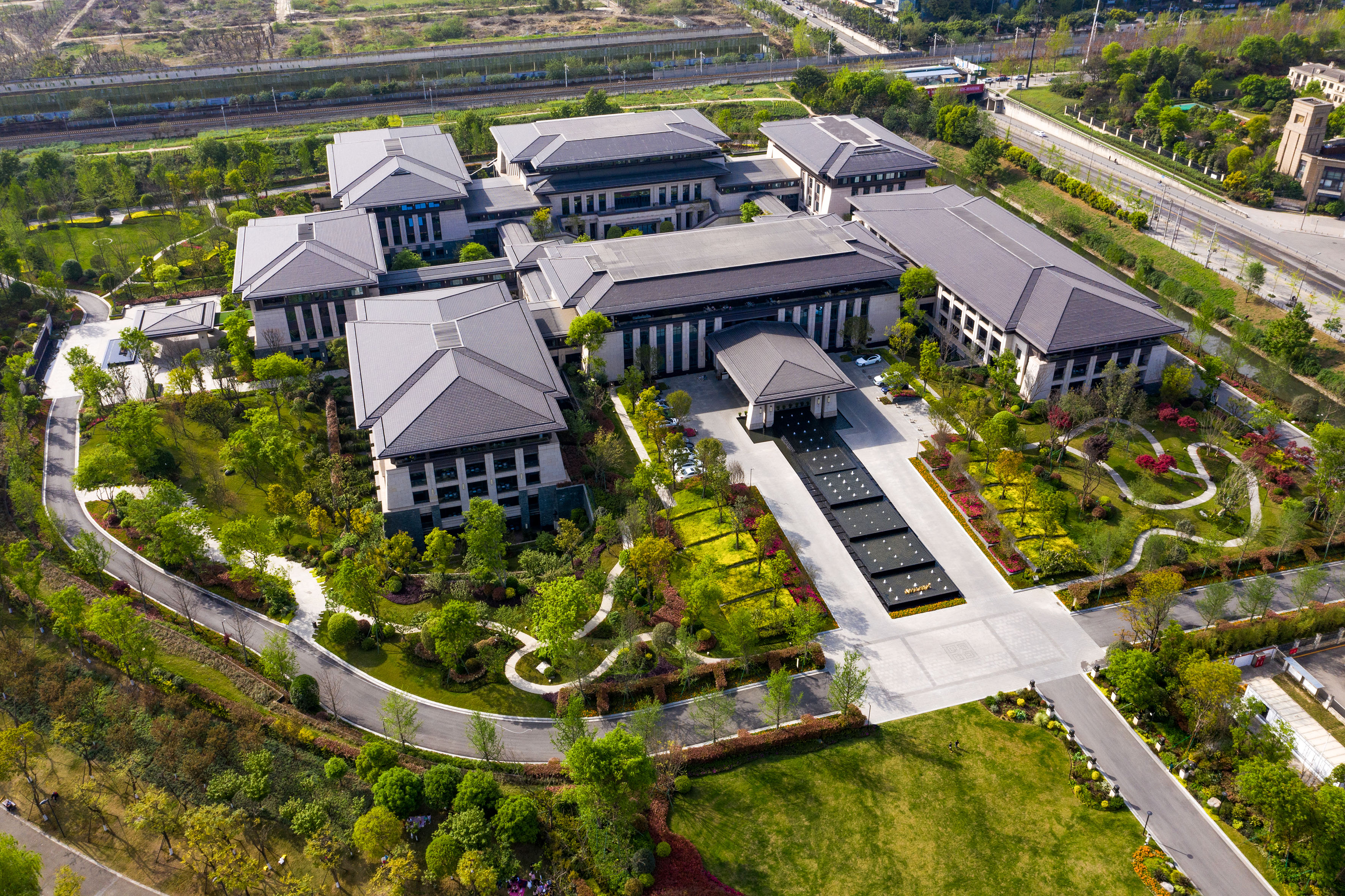 Aerial: Modern Chinese-style complex with traditional roofs and lush gardens.