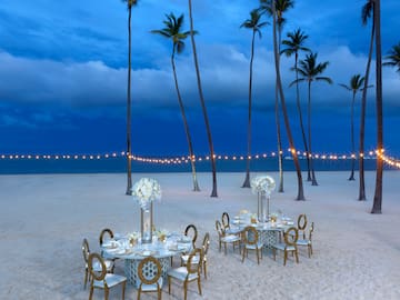 a table set up on a beach with palm trees
