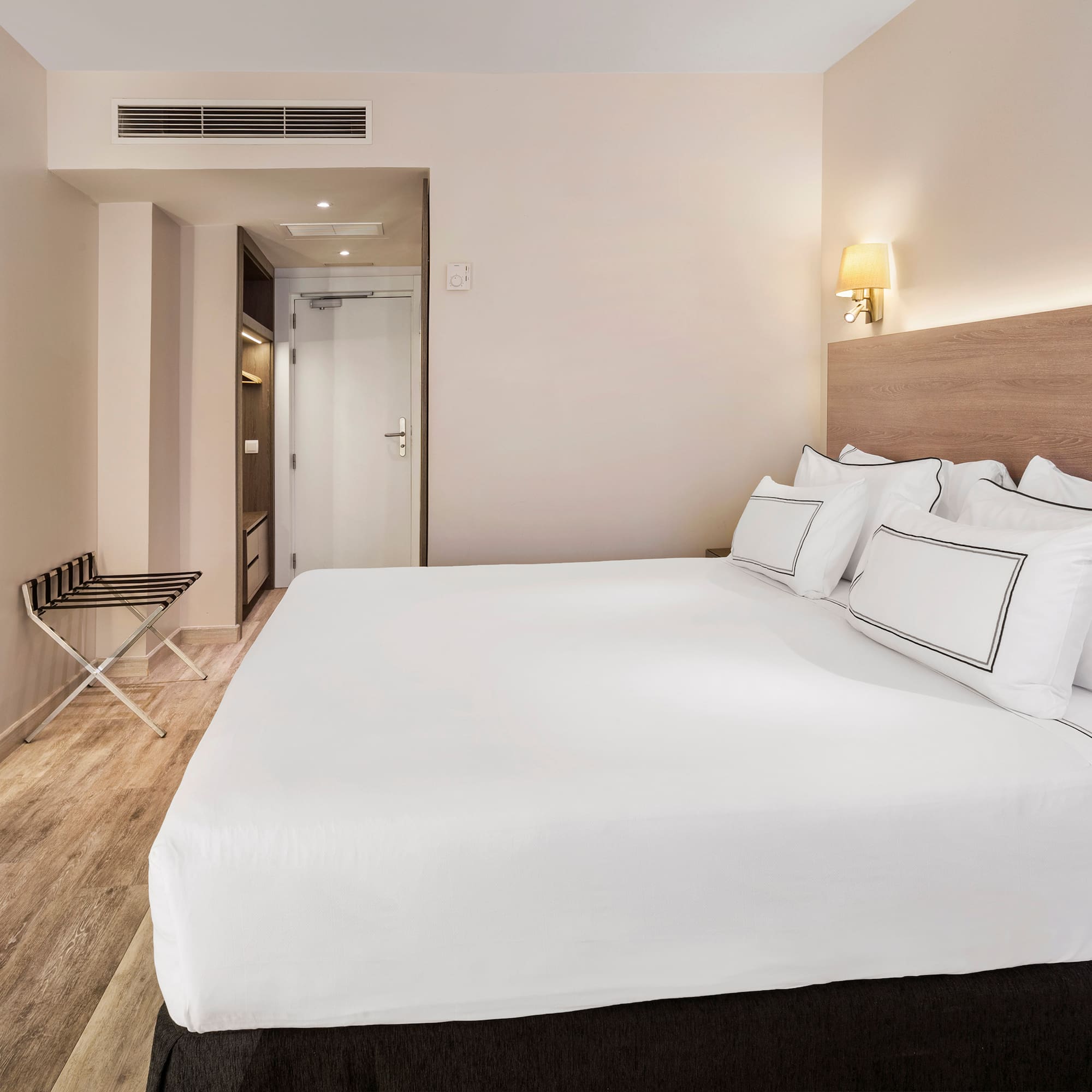 a bed with white sheets and a wood floor