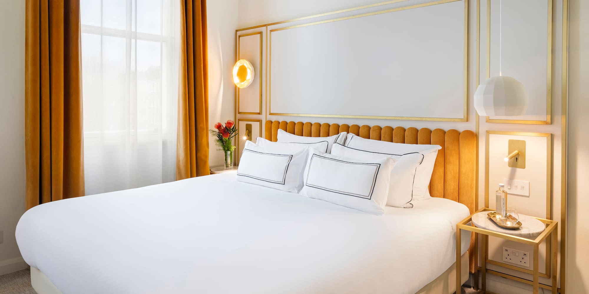 a bed with a gold headboard and a lamp