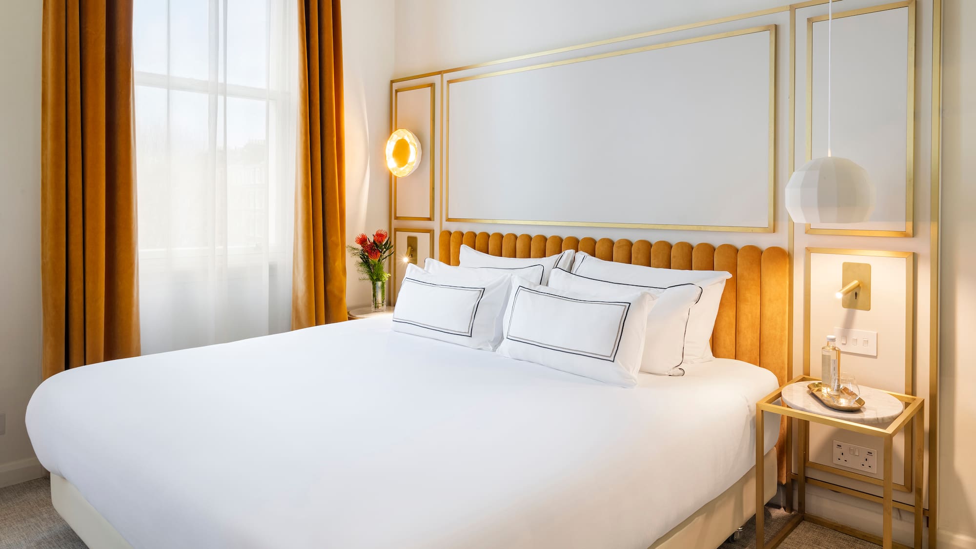 a bed with a gold headboard and a lamp