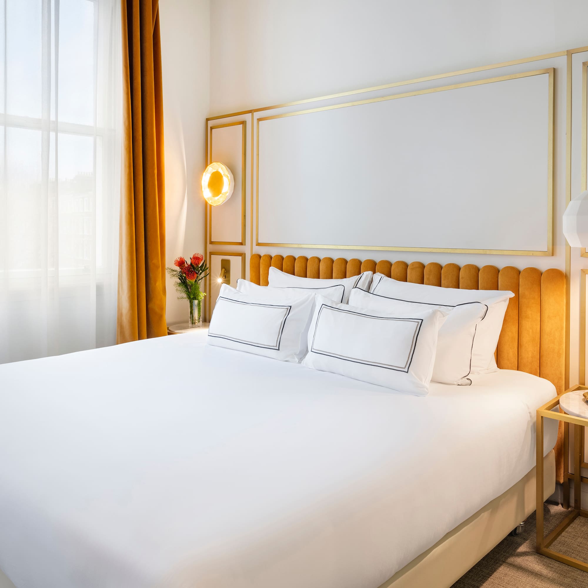 a bed with a gold headboard and a lamp