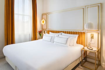 a bed with a gold headboard and a lamp