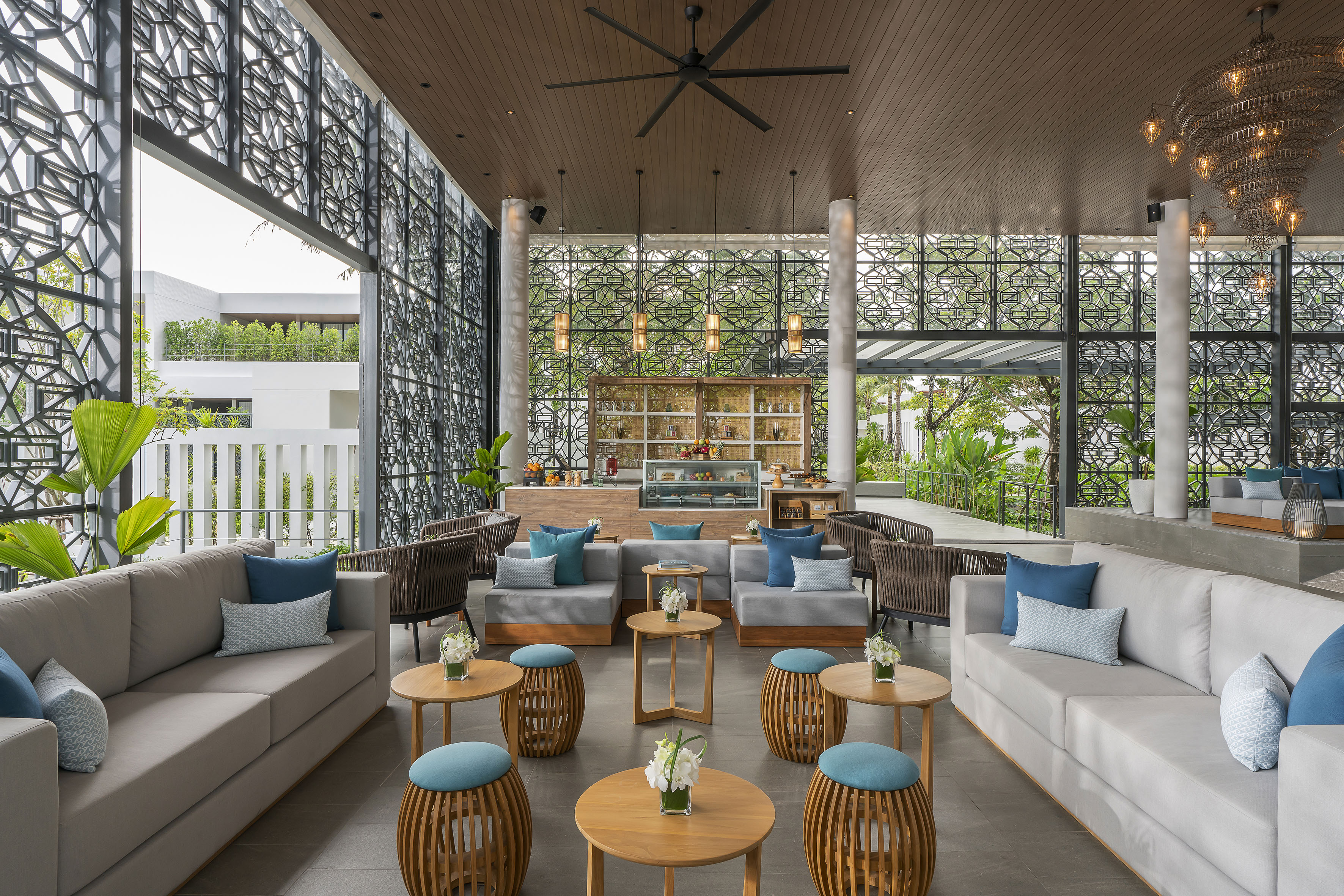 Modern hotel lounge with comfortable seating, cafe bar, and geometric screens.