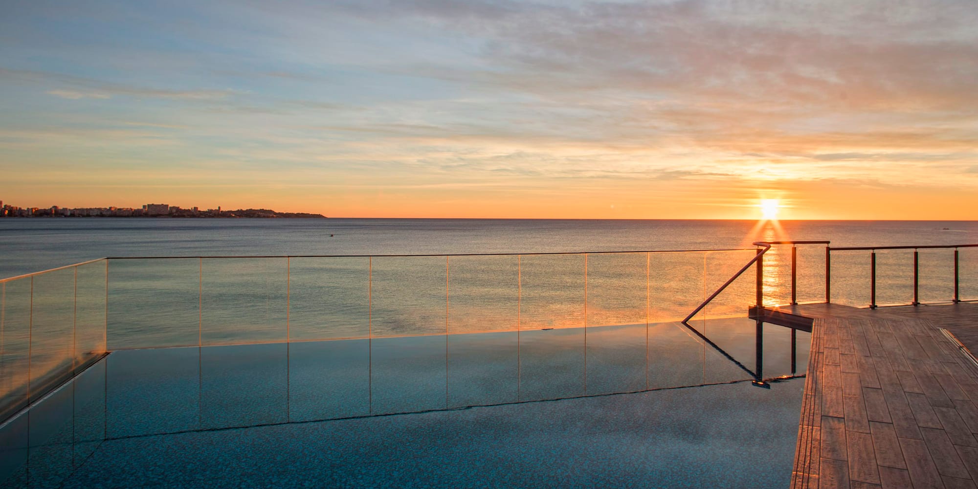 a pool with a railing and a body of water in the background
