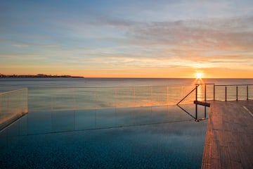 a pool with a railing and a body of water in the background