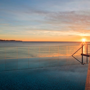 a pool with a railing and a body of water in the background