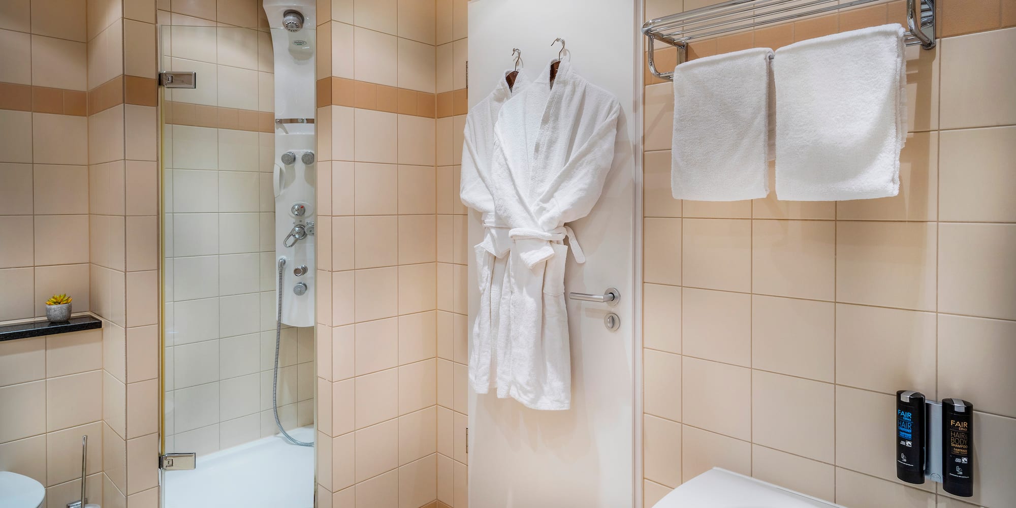 a bathroom with white bathrobes and towels