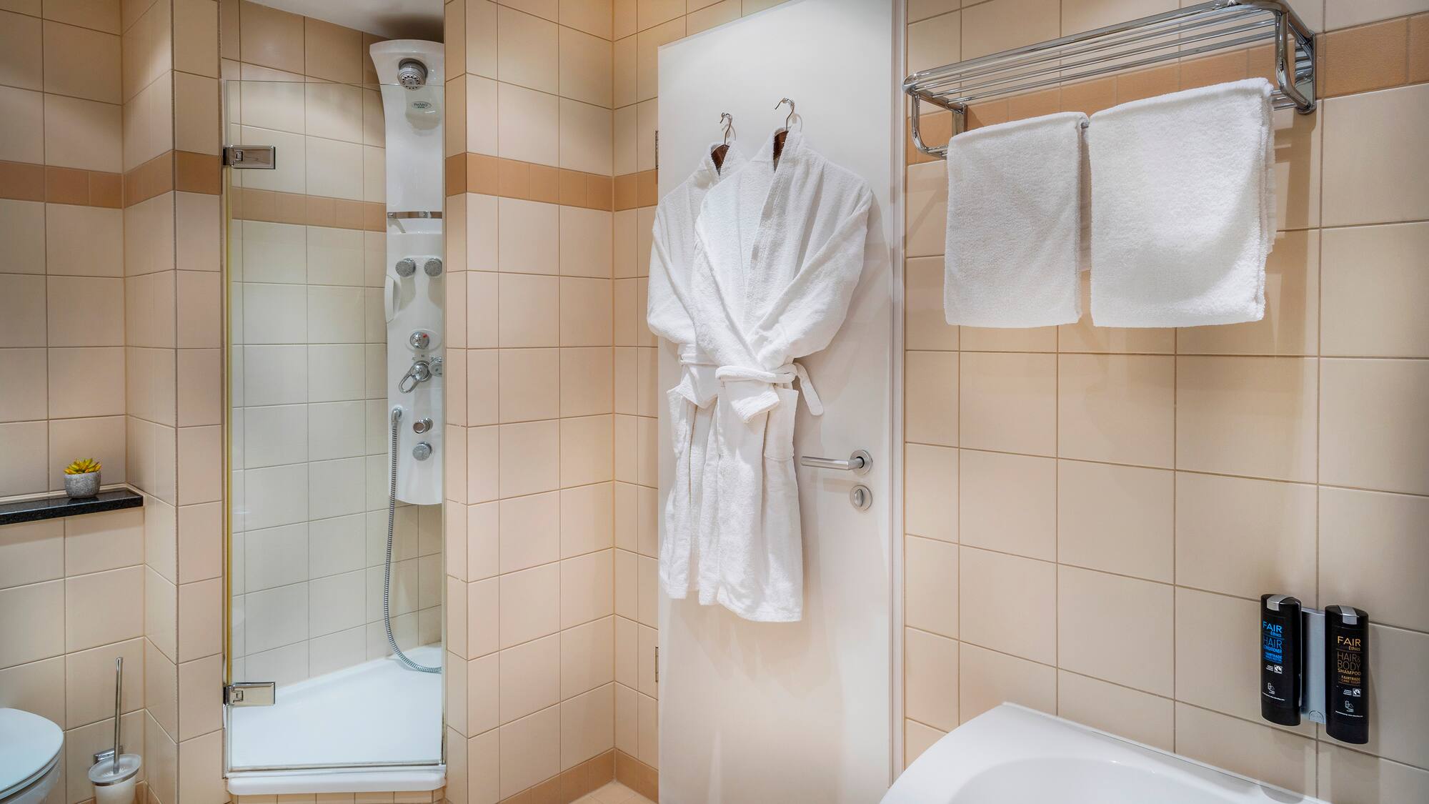 a bathroom with white bathrobes and towels