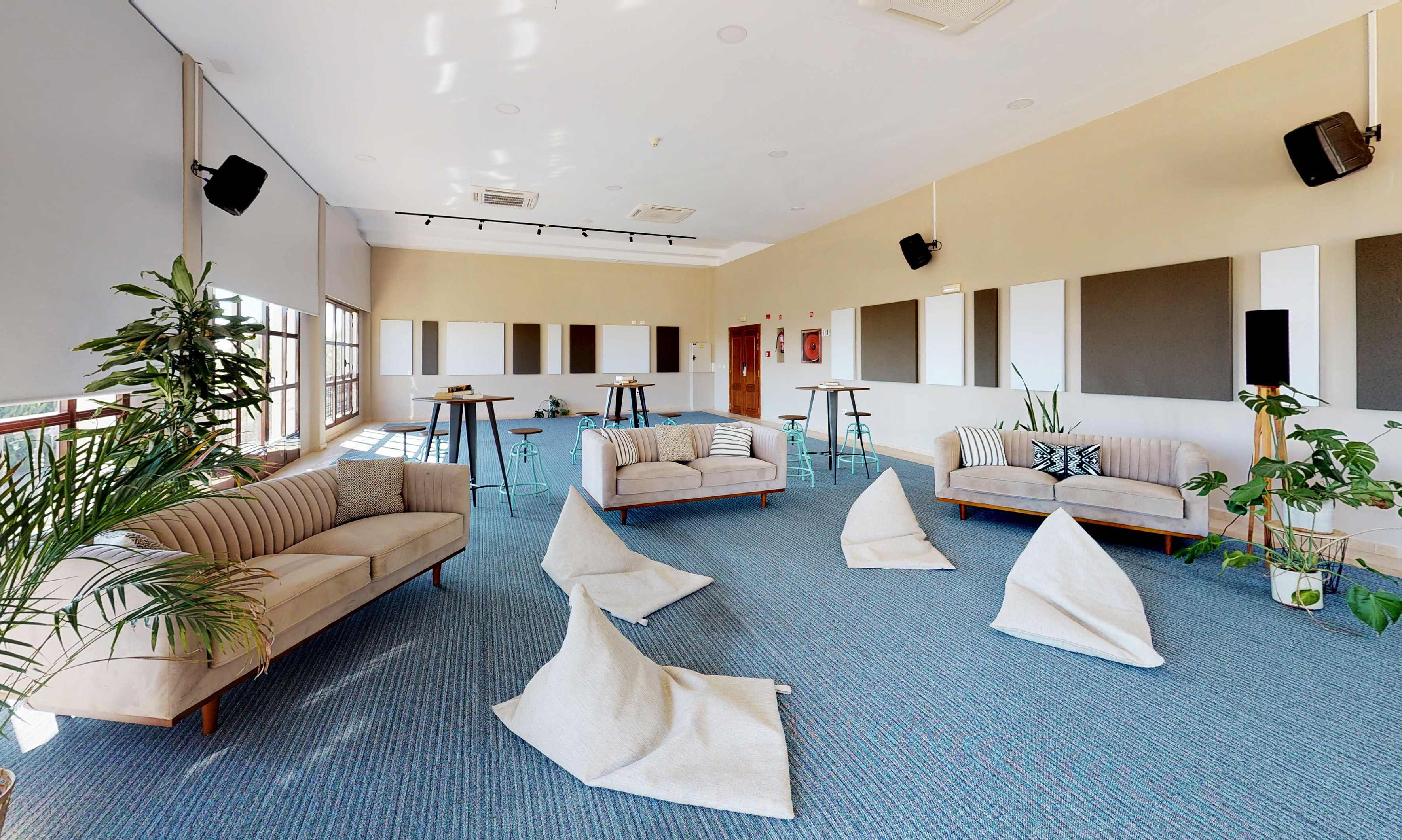 Modern lounge event space with sofas, bean bags, high tables, and plants.