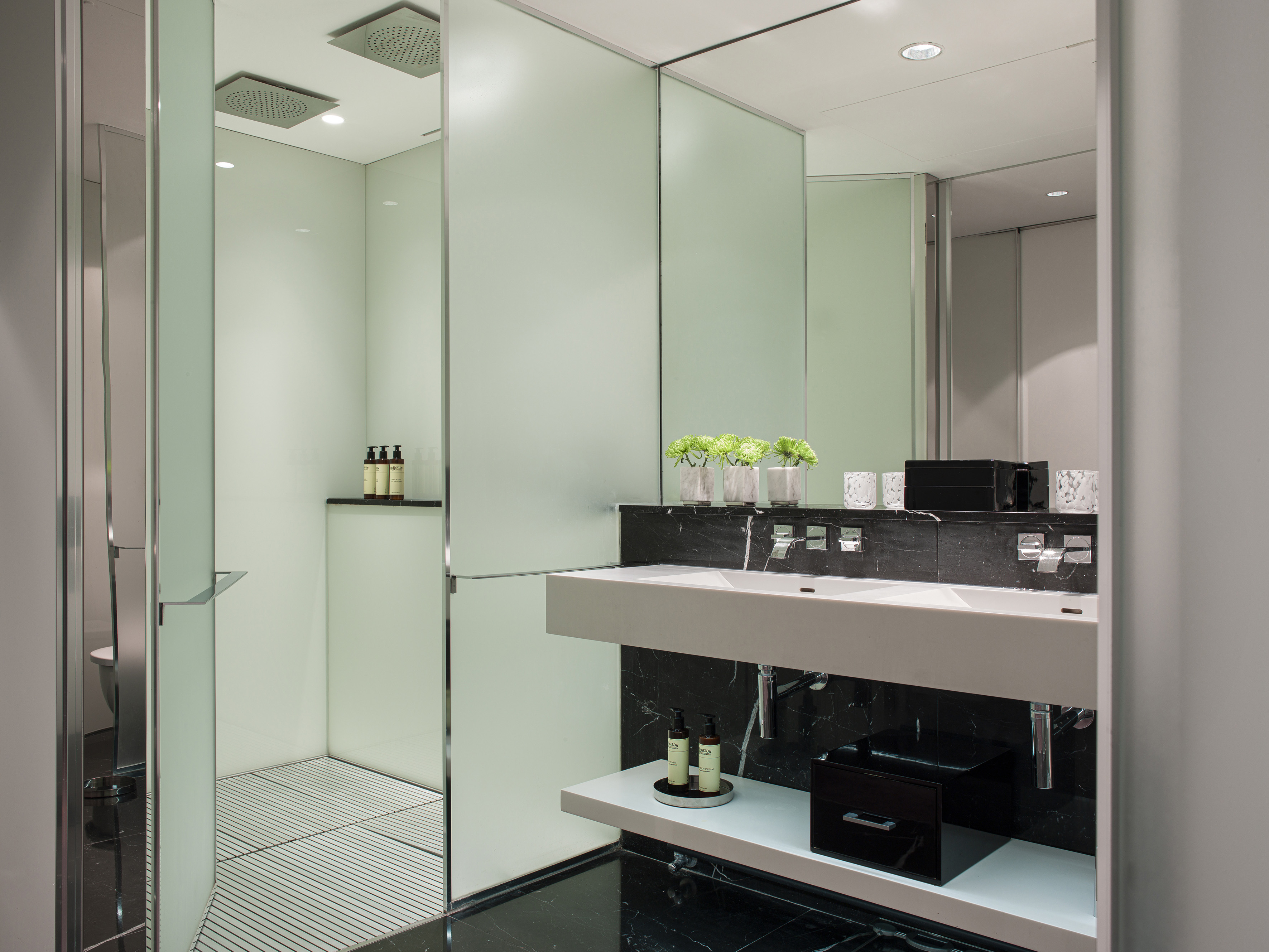 Luxury bathroom: walk-in shower, double vanity, frosted glass panels, black marble.