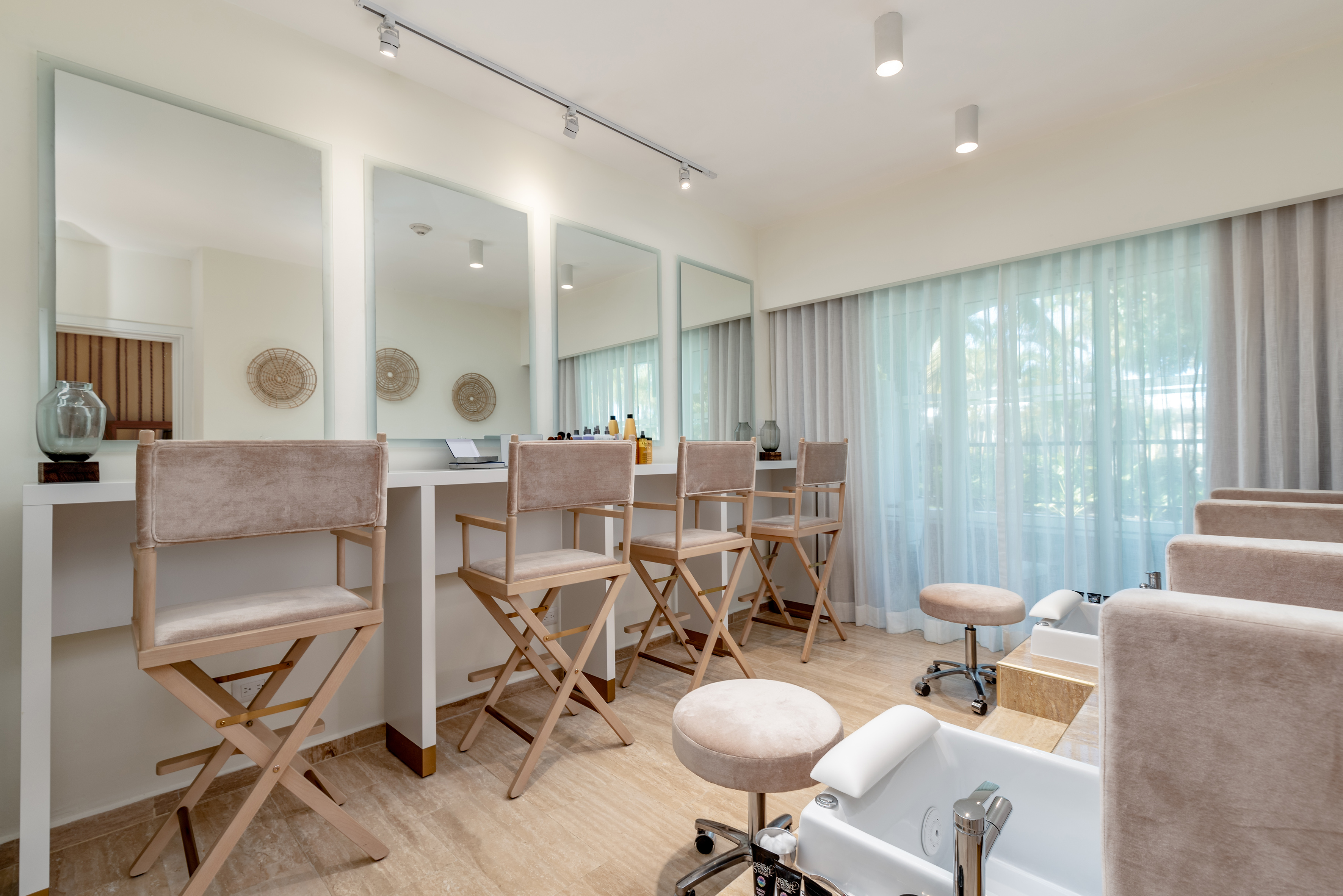 Luxury spa salon with makeup stations, pedicure chairs, and large mirrors.
