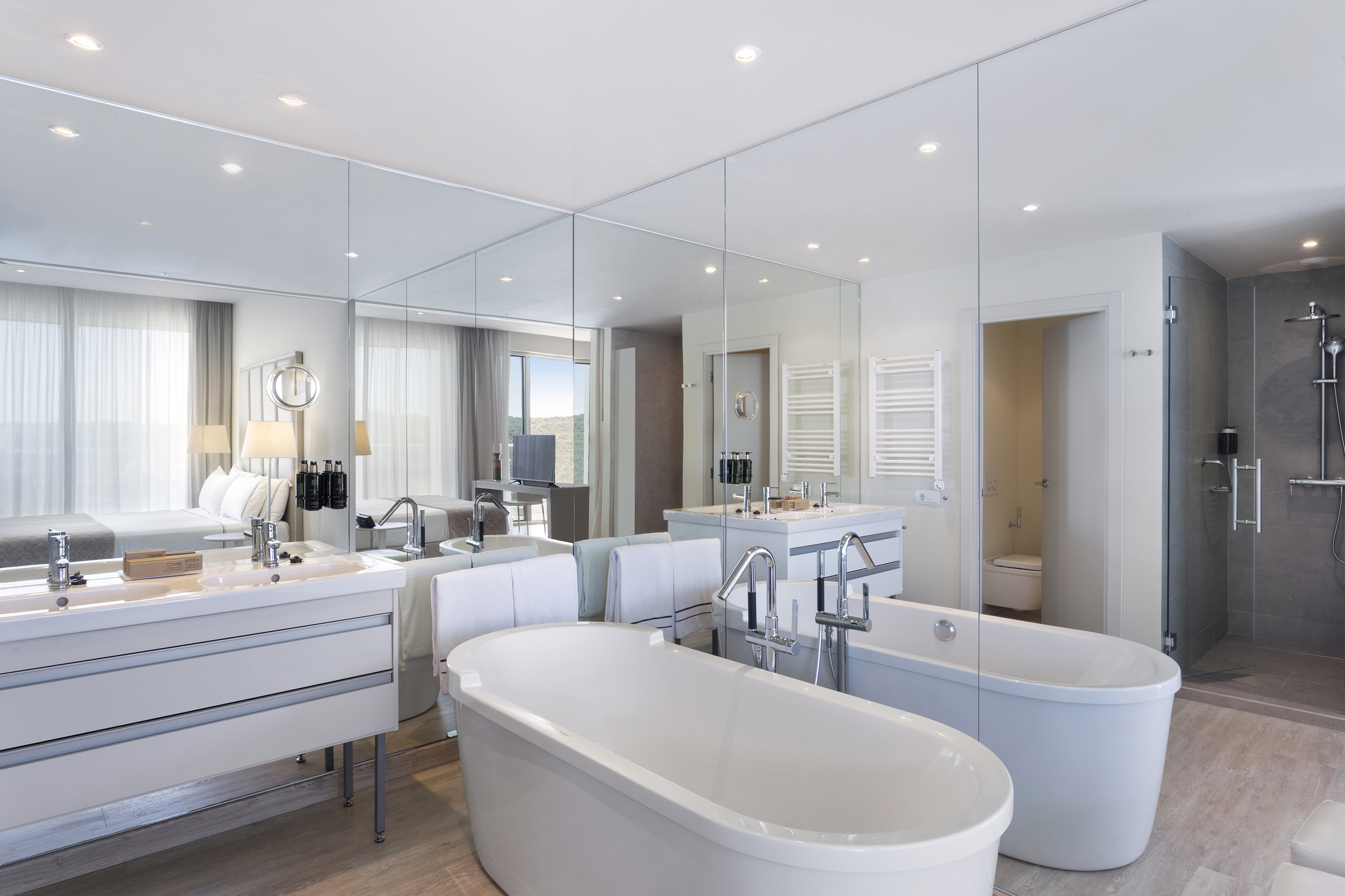 Luxury hotel bathroom with dual freestanding tubs, double vanity, shower.