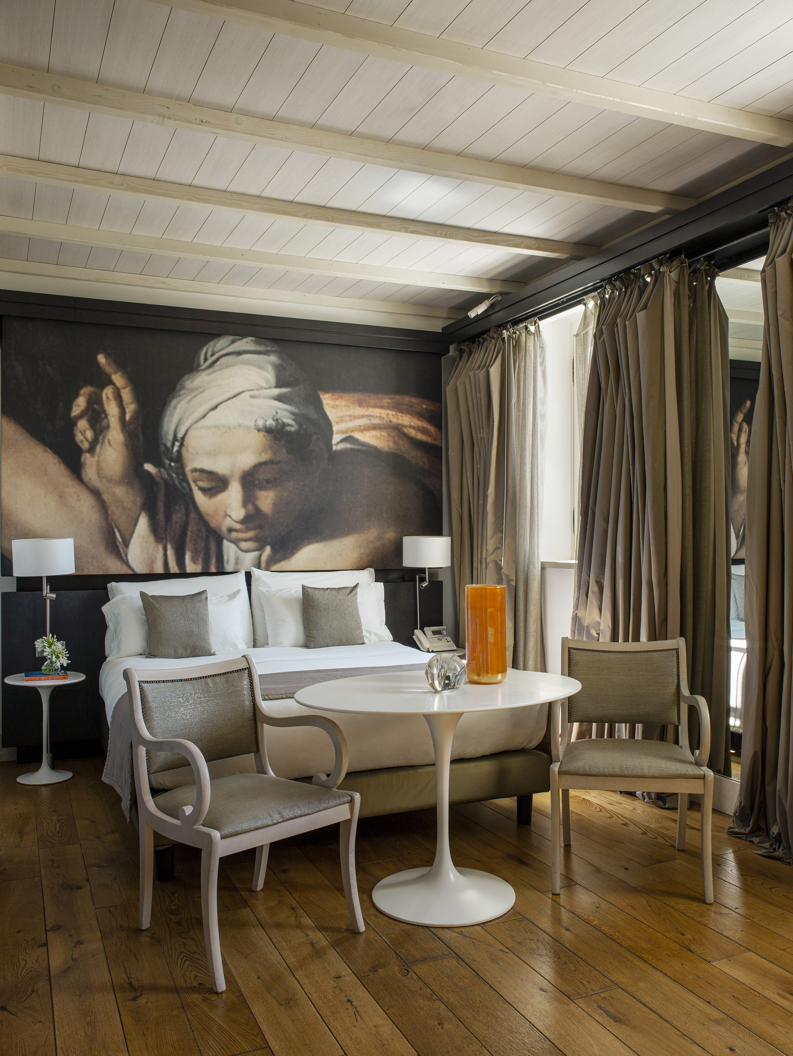Elegant hotel bedroom with classical art mural, wood ceiling, and modern furniture.