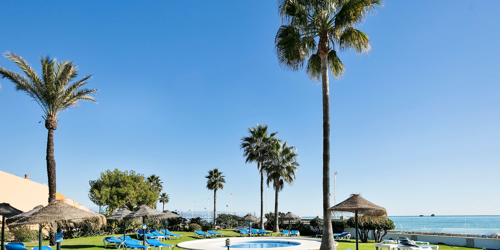 a pool with lounge chairs and umbrellas by a beach