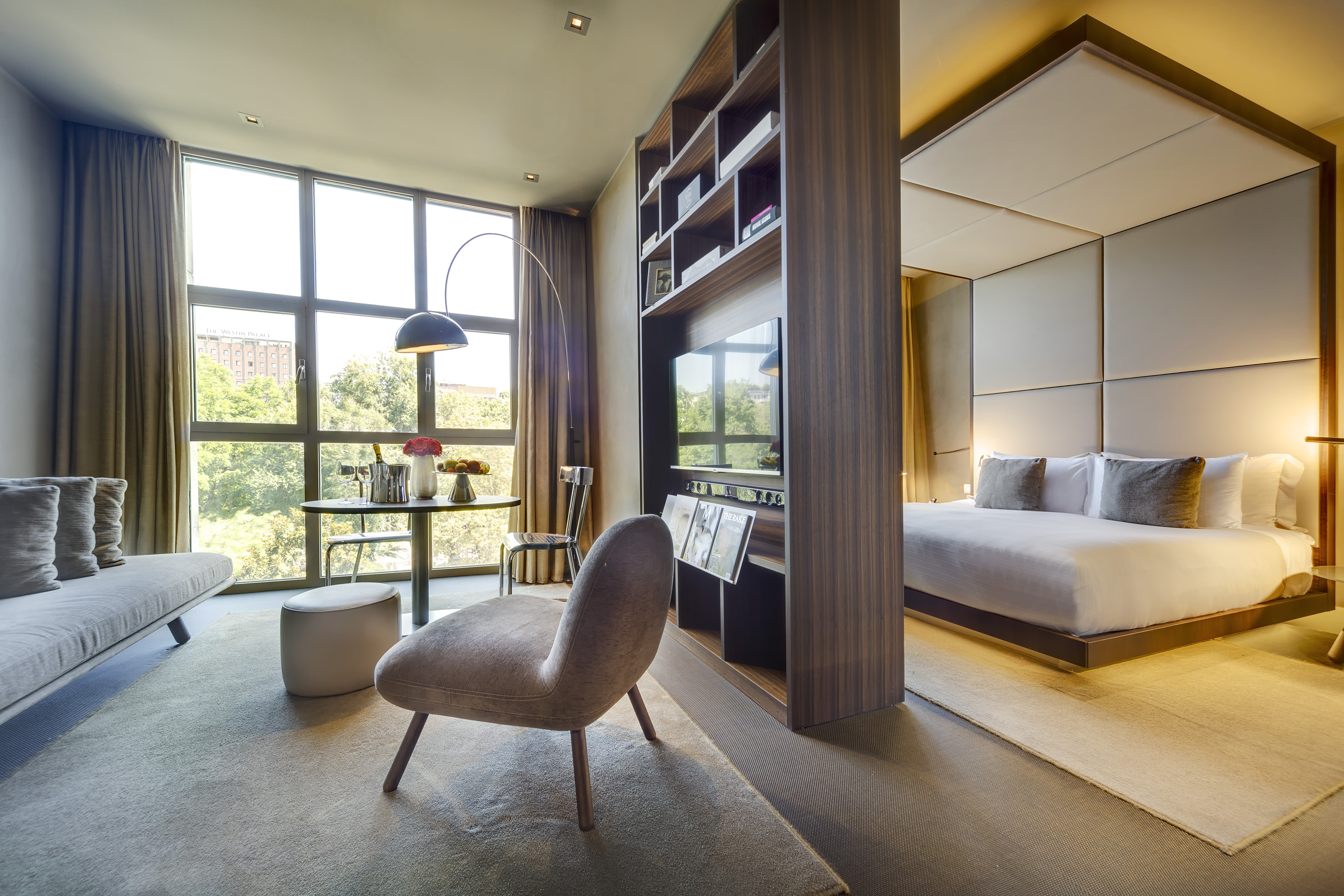 Modern hotel suite, living area with large window, and elegant bedroom.