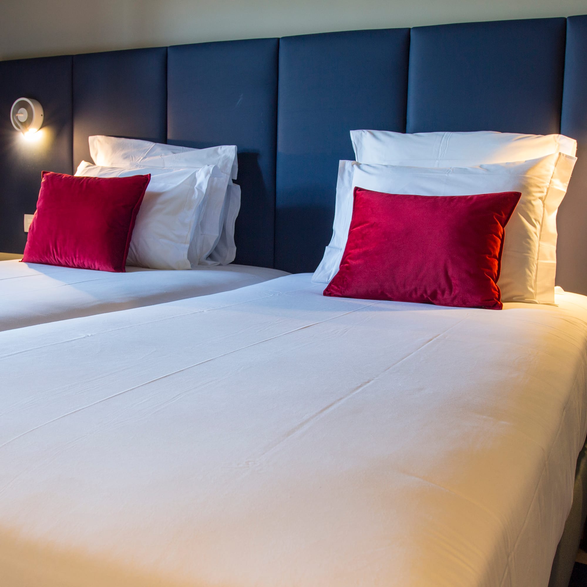 a bed with white sheets and red pillows