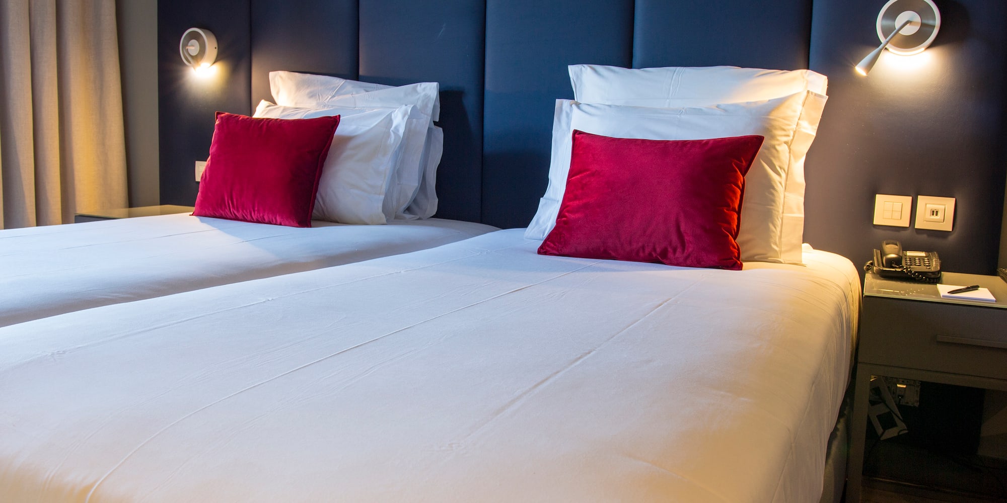 a bed with white sheets and red pillows