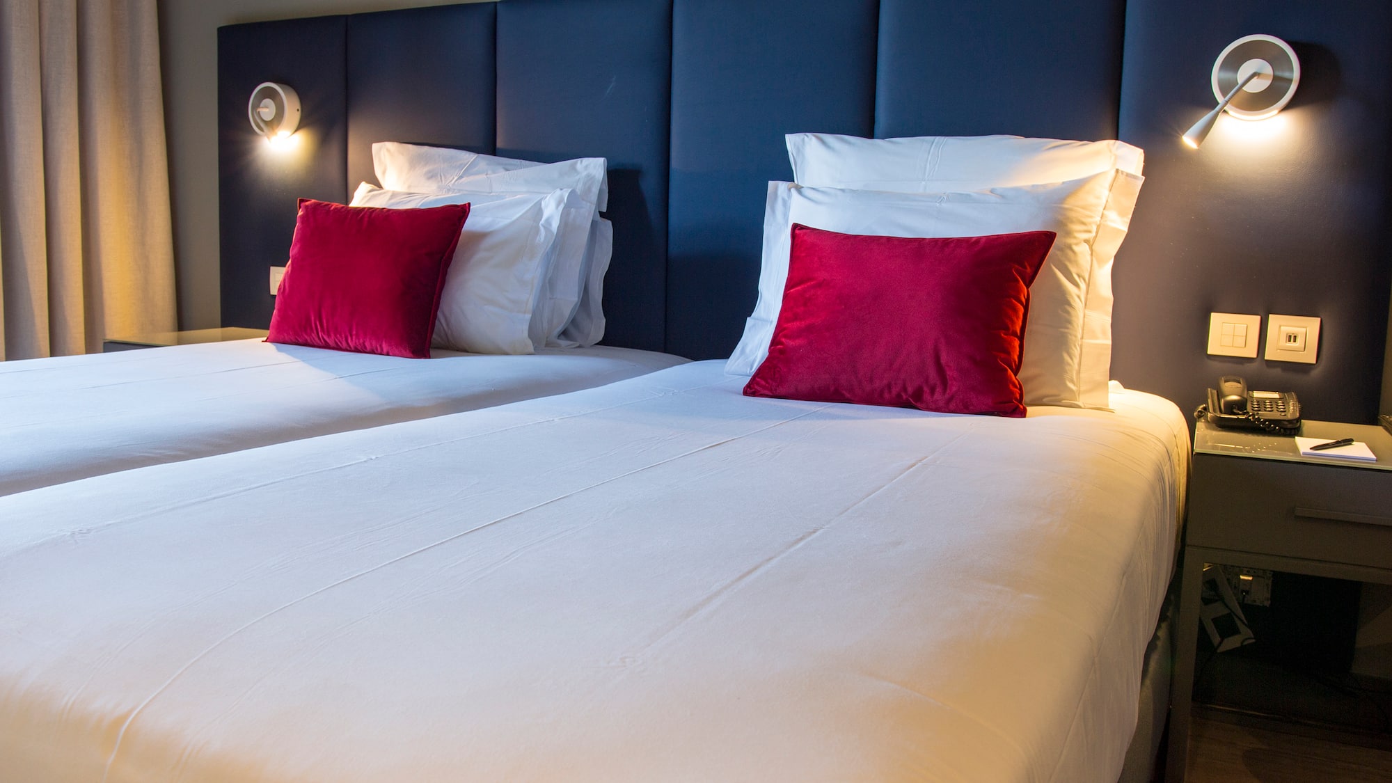 a bed with white sheets and red pillows