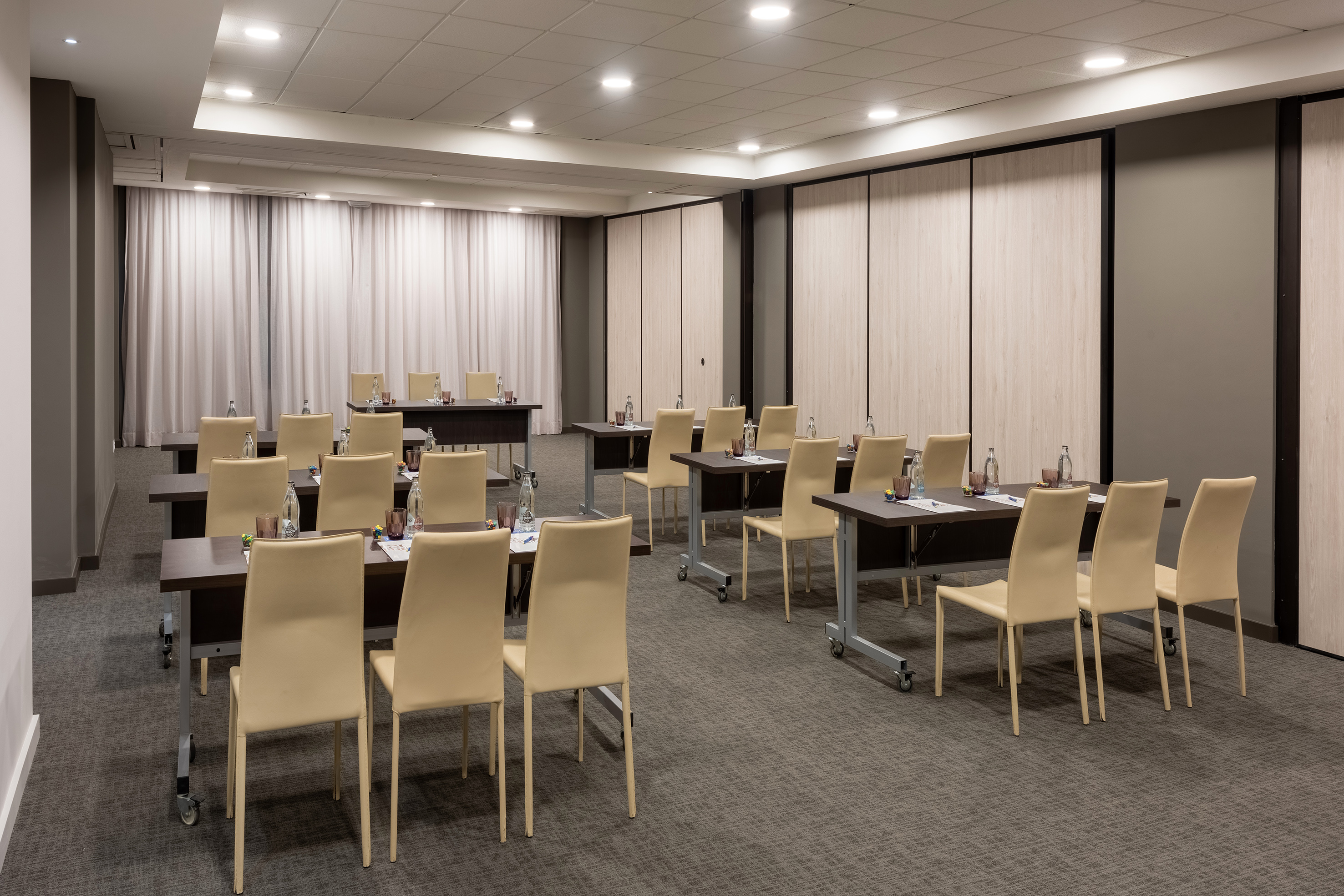 Modern corporate meeting room with rows of tables and chairs.