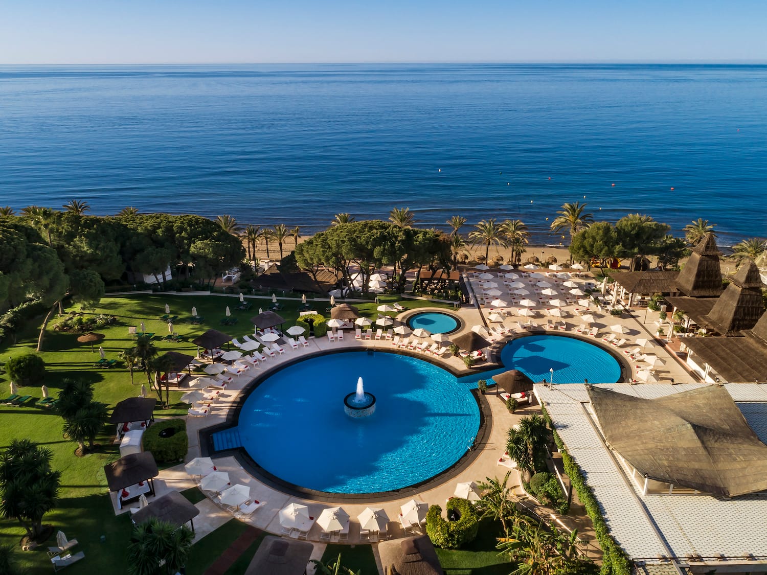 a swimming pool with a fountain surrounded by trees and a body of water