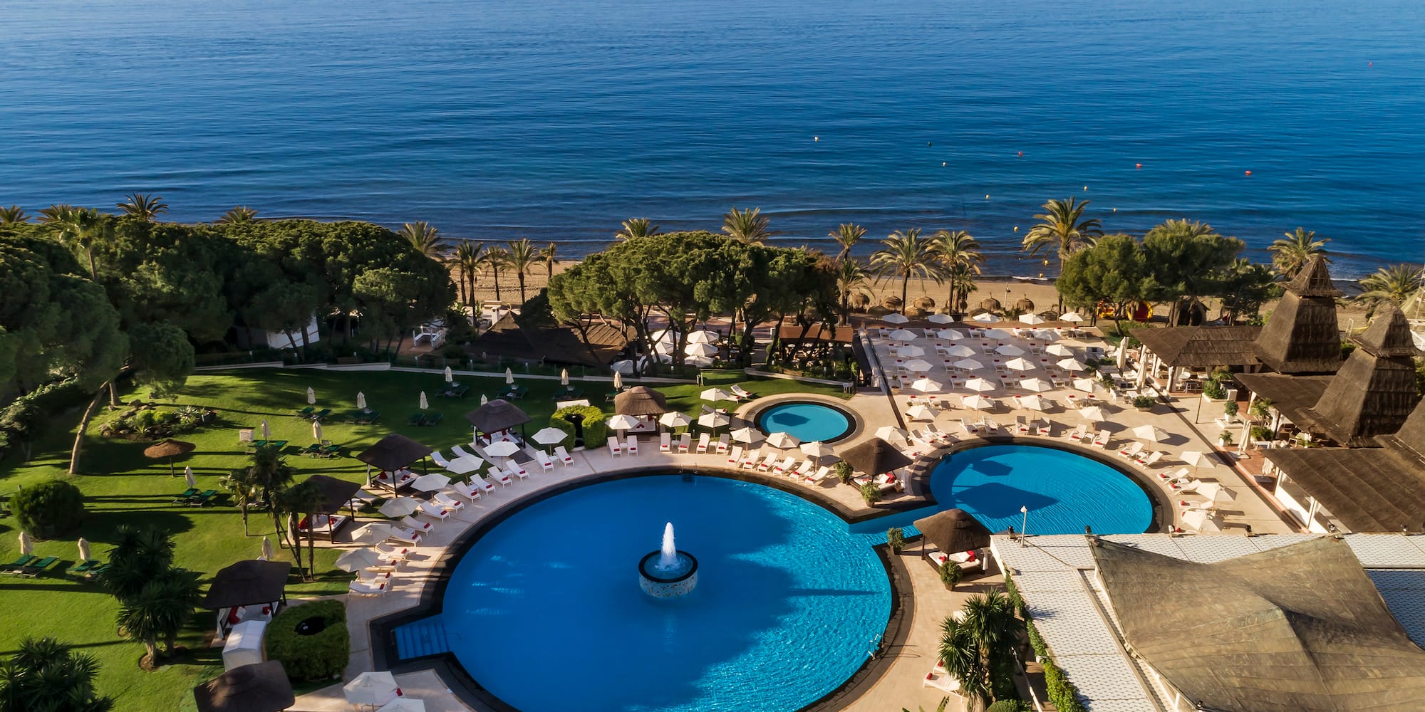 a swimming pool with a fountain surrounded by trees and a body of water