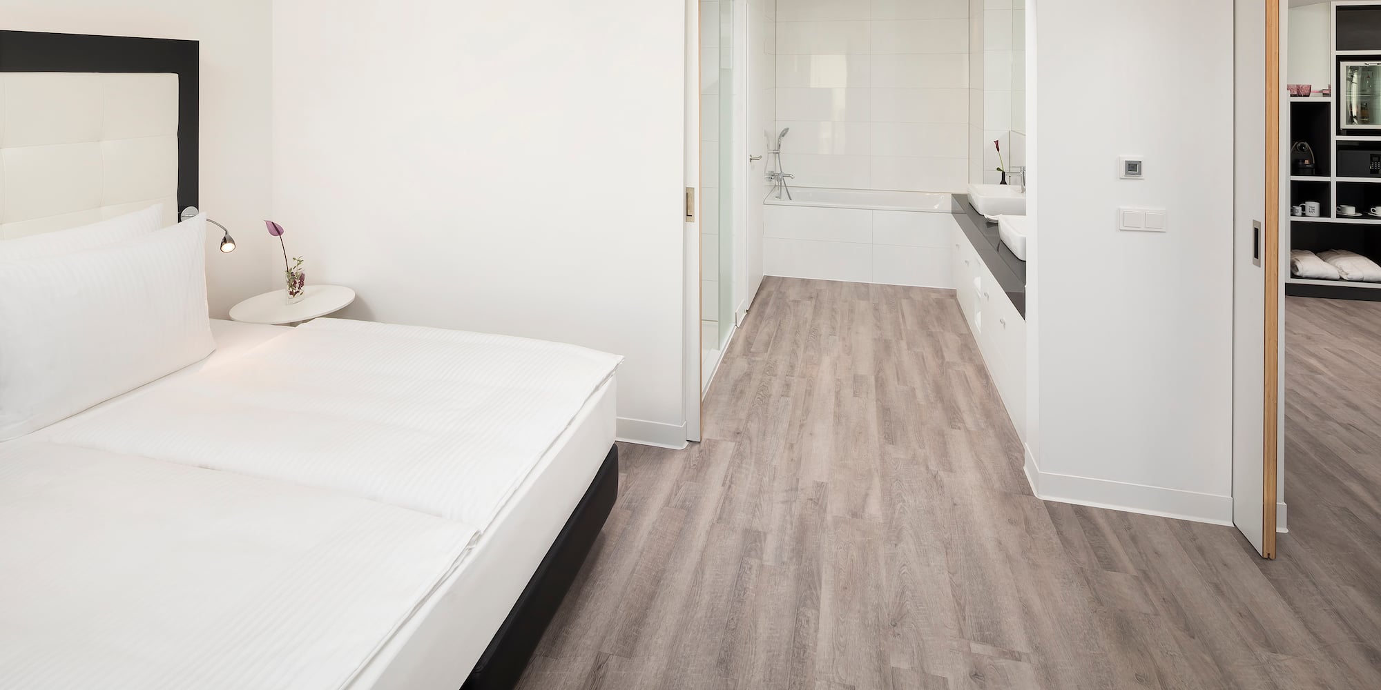 a bedroom with a wood floor and a white bed