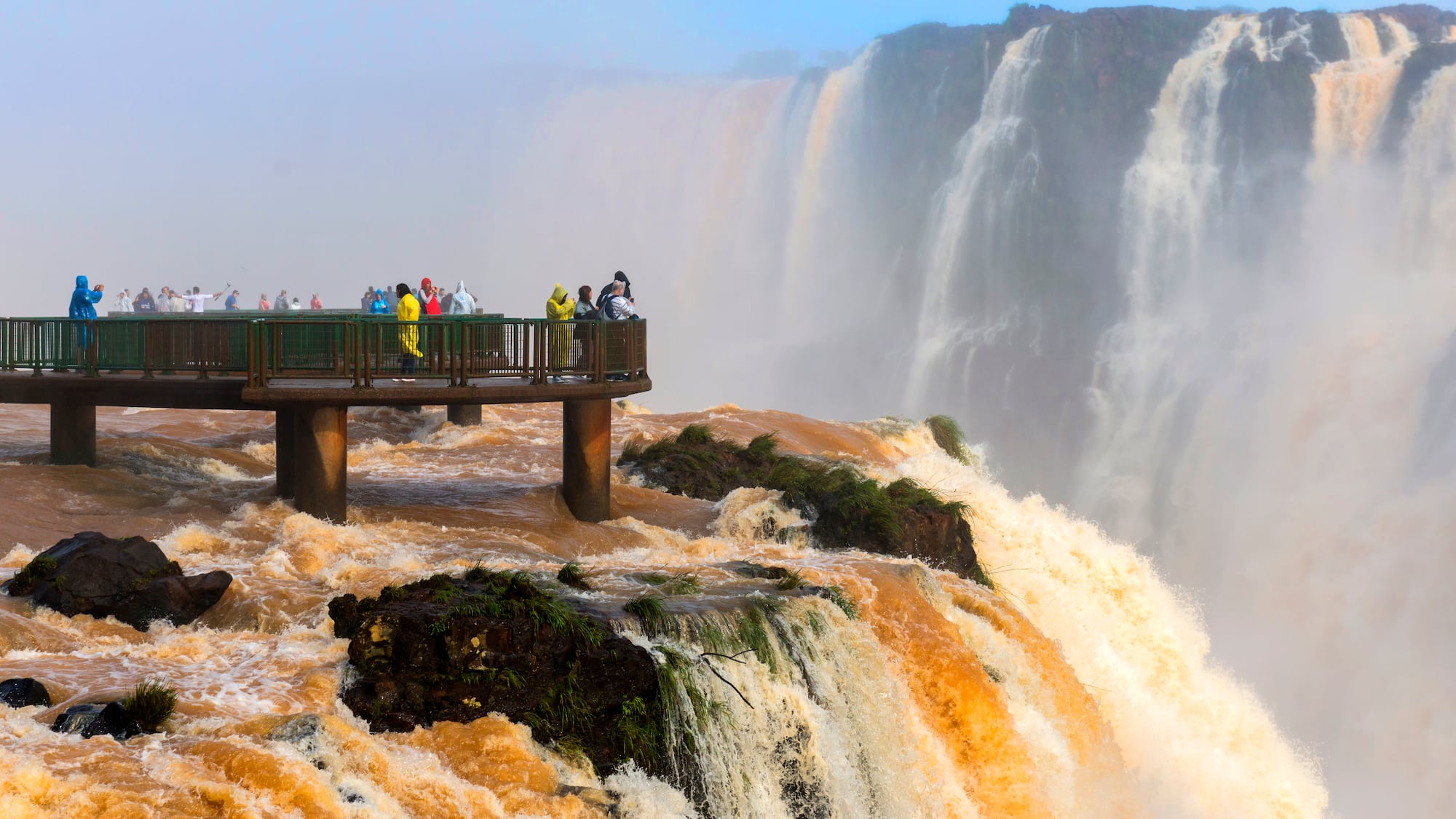 a group of people standing on a bridge over a large waterfall