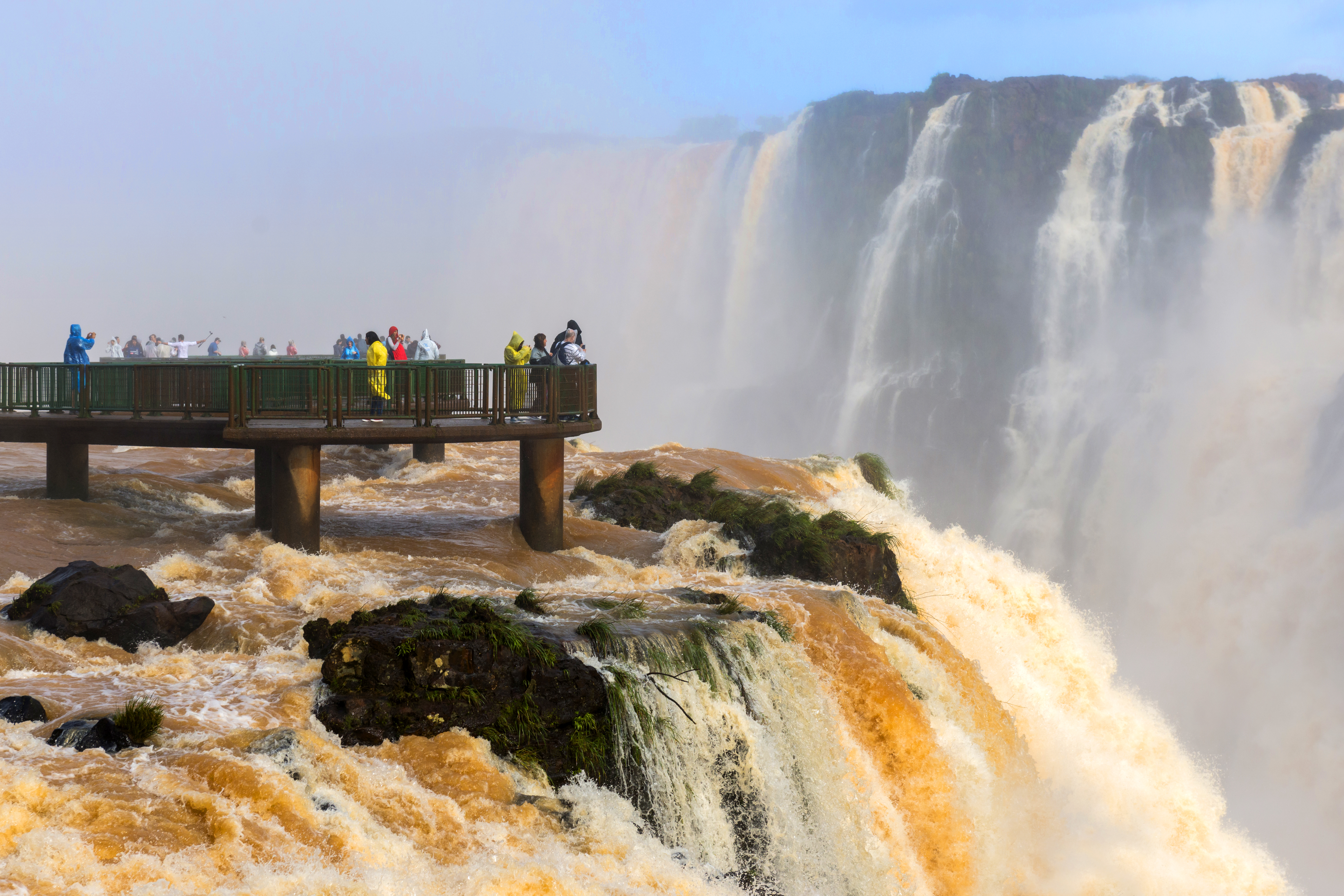 a group of people standing on a bridge over a large waterfall