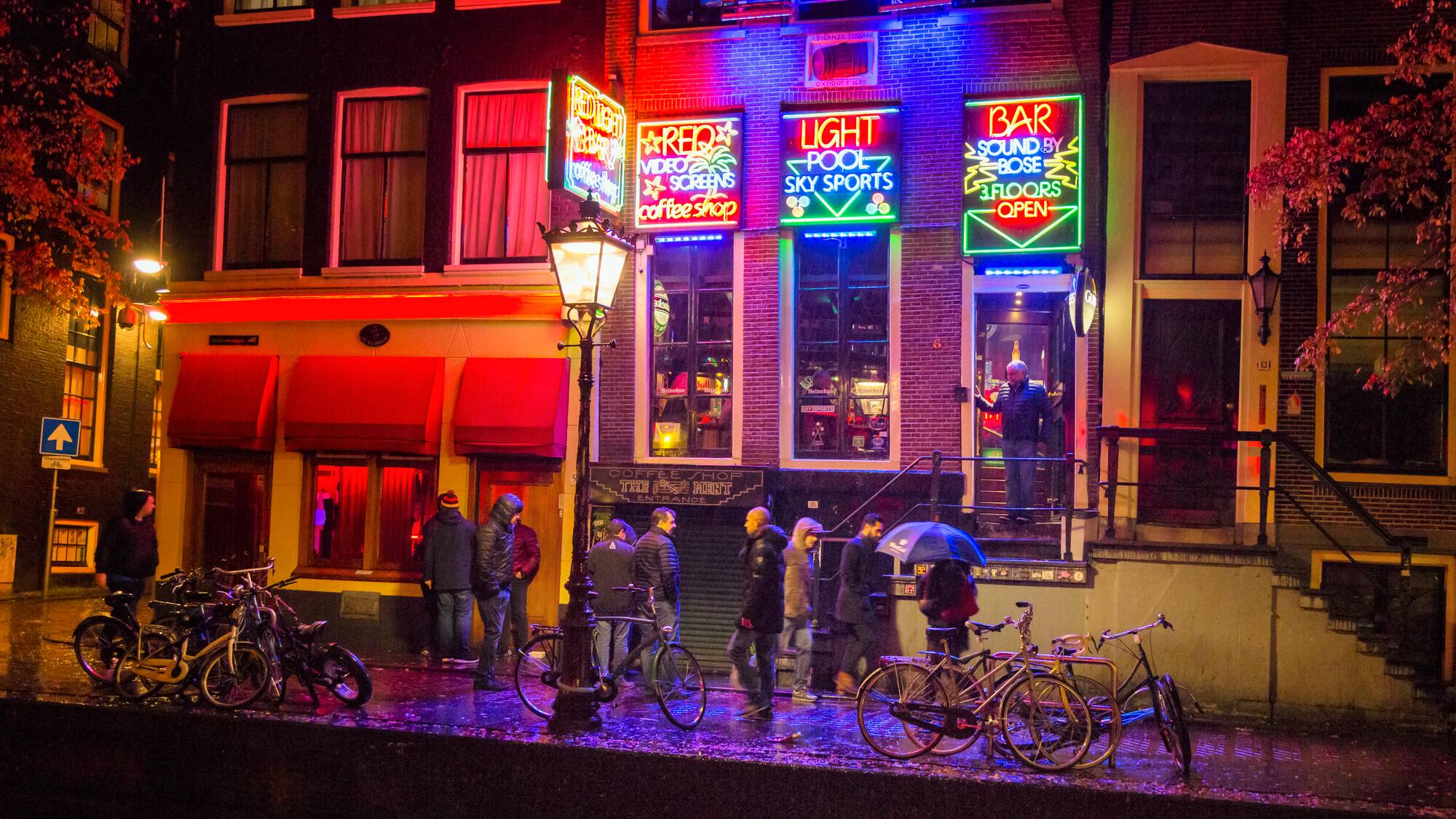 a group of people standing outside of a building with neon signs