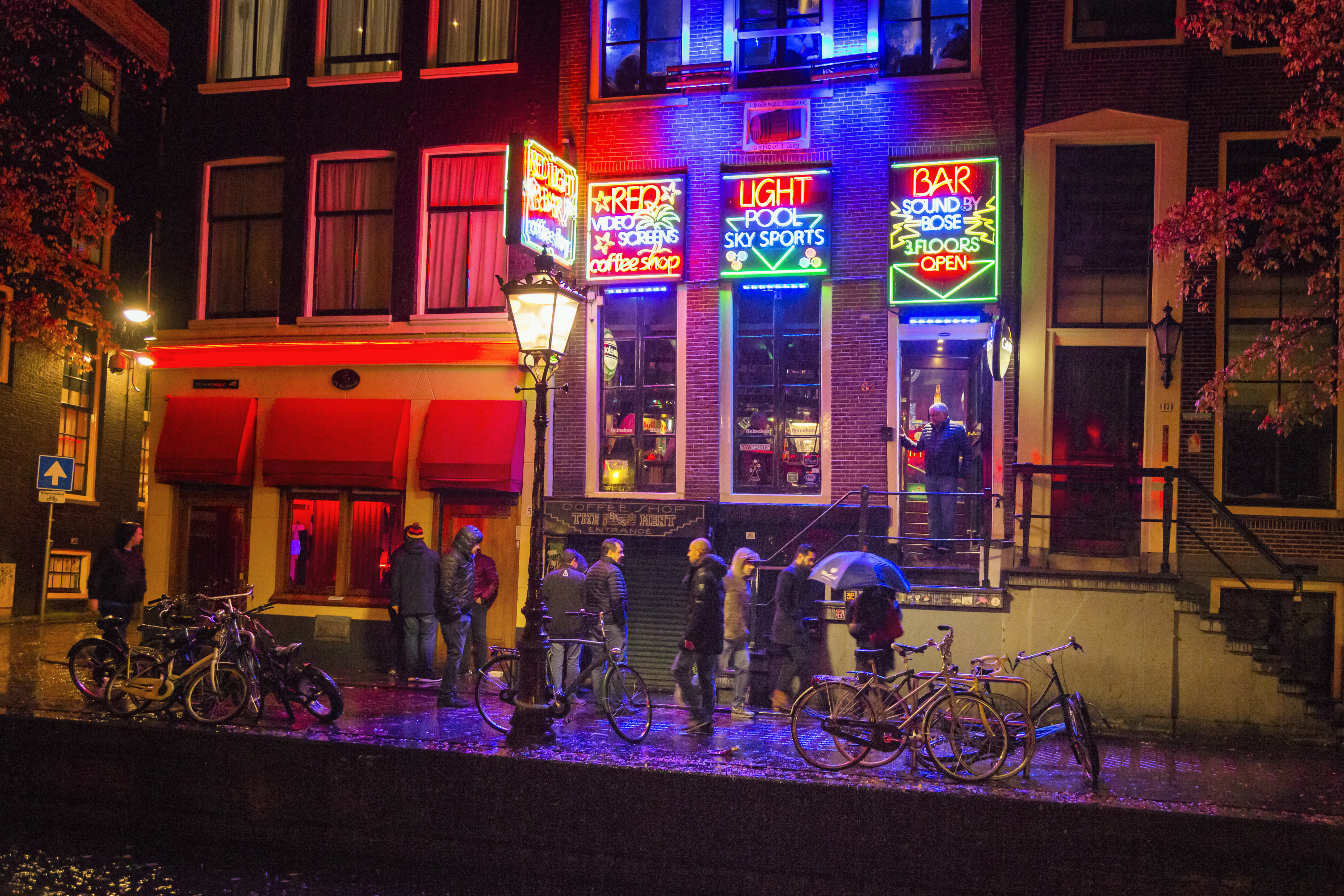 a group of people standing outside of a building with neon signs