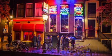 a group of people standing outside of a building with neon signs