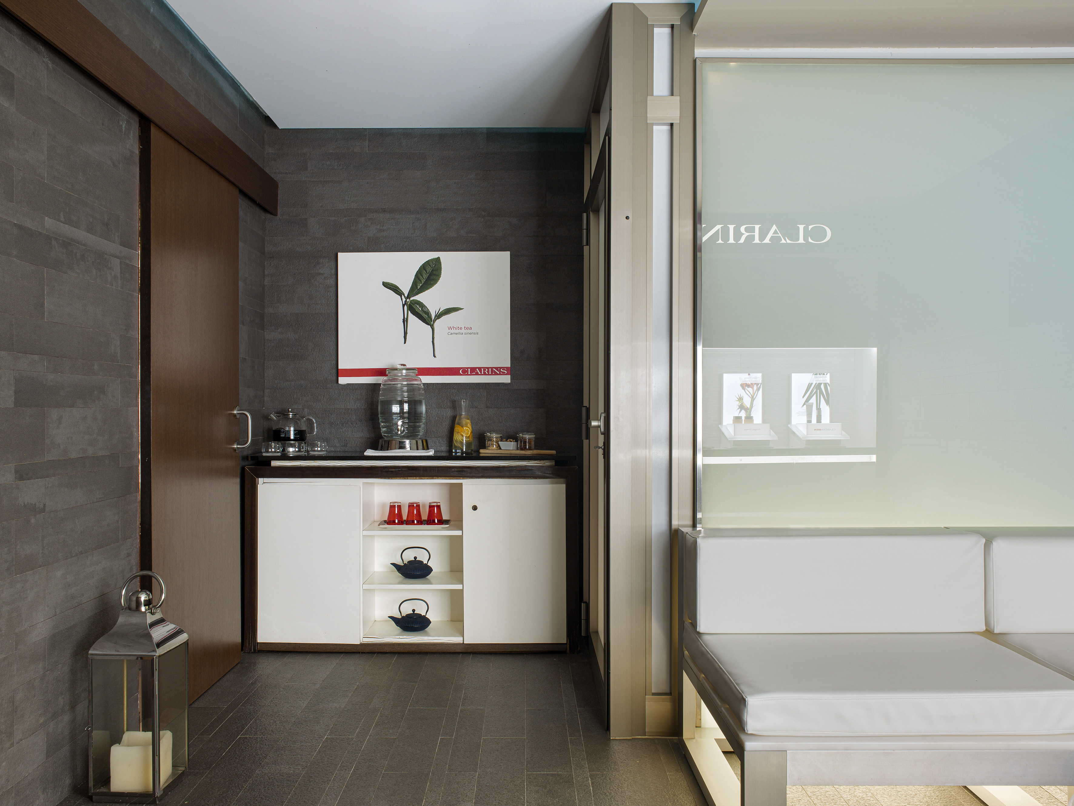 Clarins spa lounge, modern refreshment station, dark tiles, white bench.