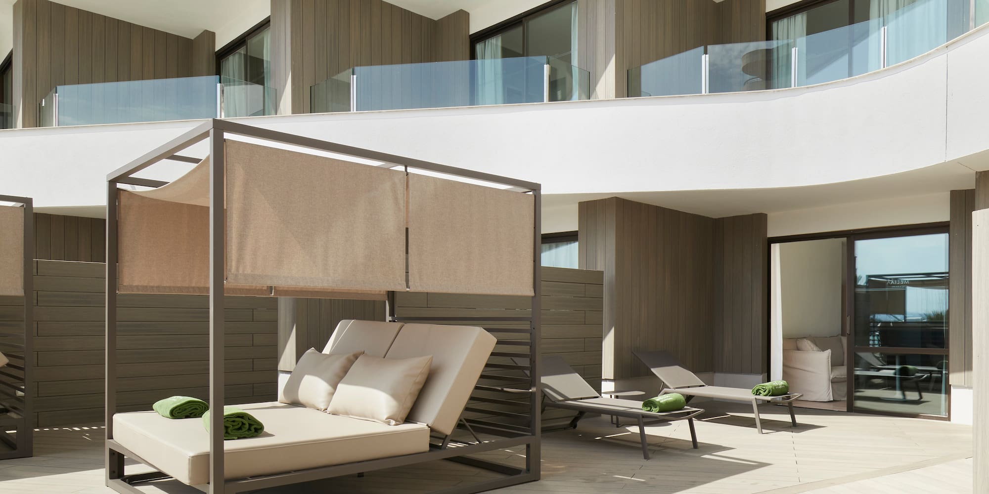 Luxury resort terrace with modern daybed and sun loungers.