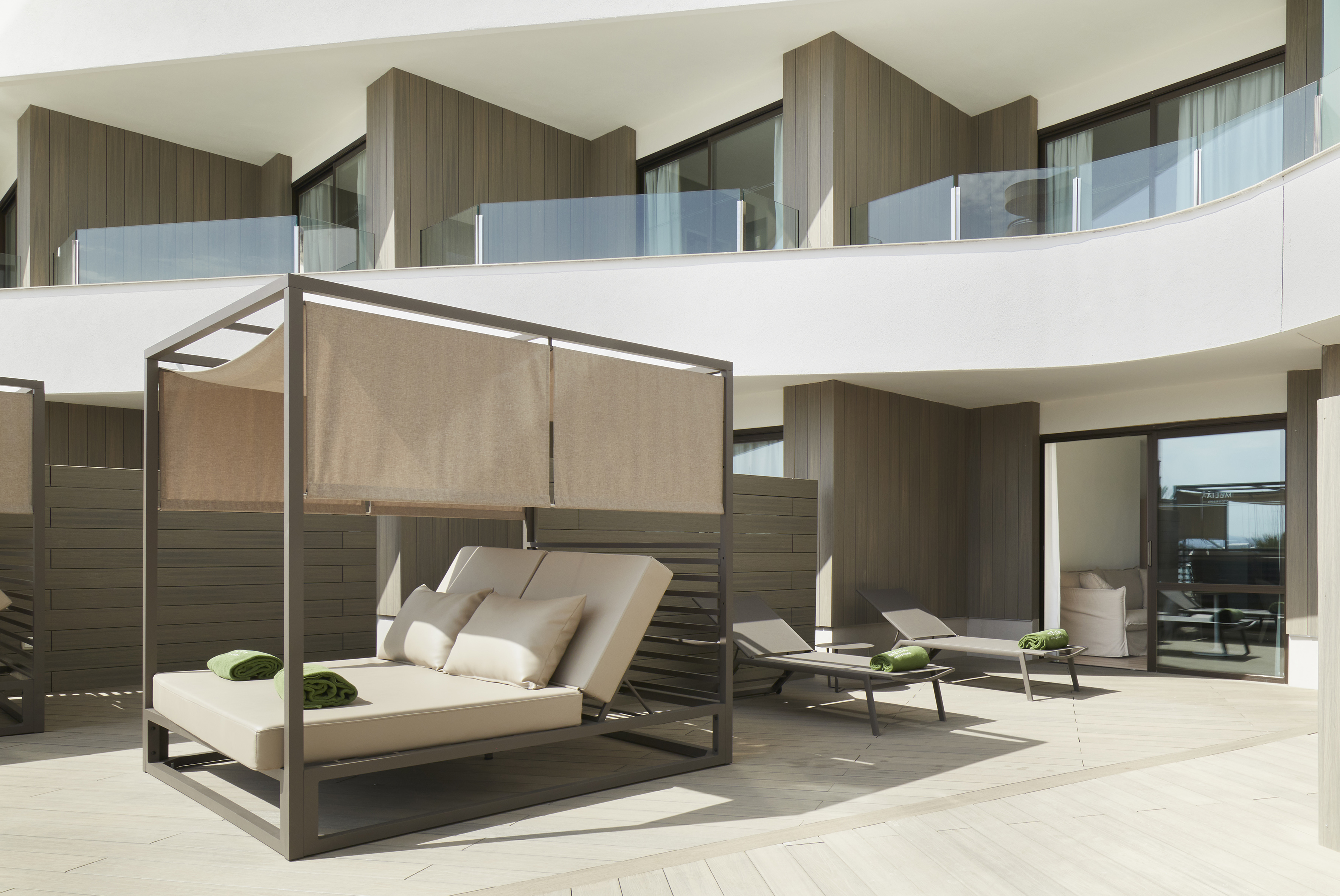 Luxury resort terrace with modern daybed and sun loungers.